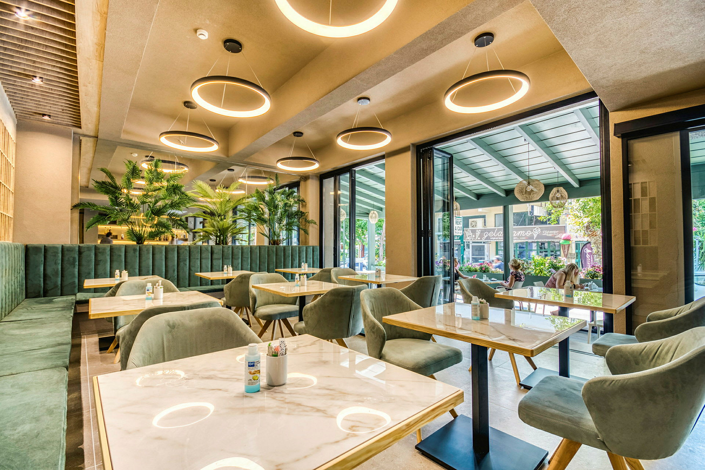 Moderni ravintola, jossa on vihreät huonekalut ja suuret ikkunat. (Tekoälyn luoma teksti)