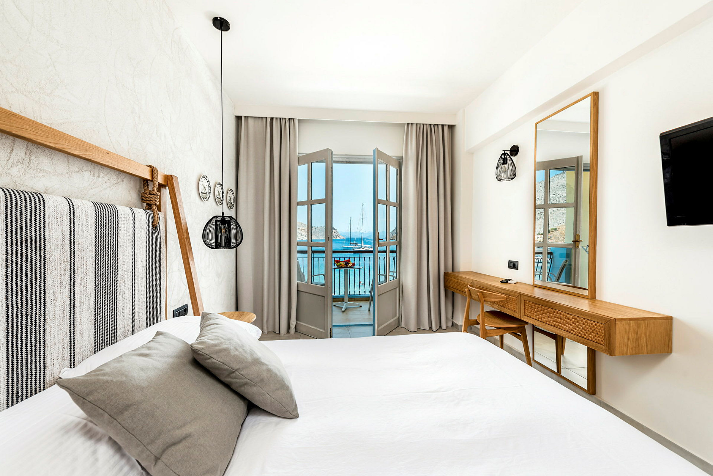 Valoisa ja modernisti sisustettu hotellihuone, jossa on sänky ja näkymä merelle parvekkeelta. (Tekoälyn luoma teksti)
