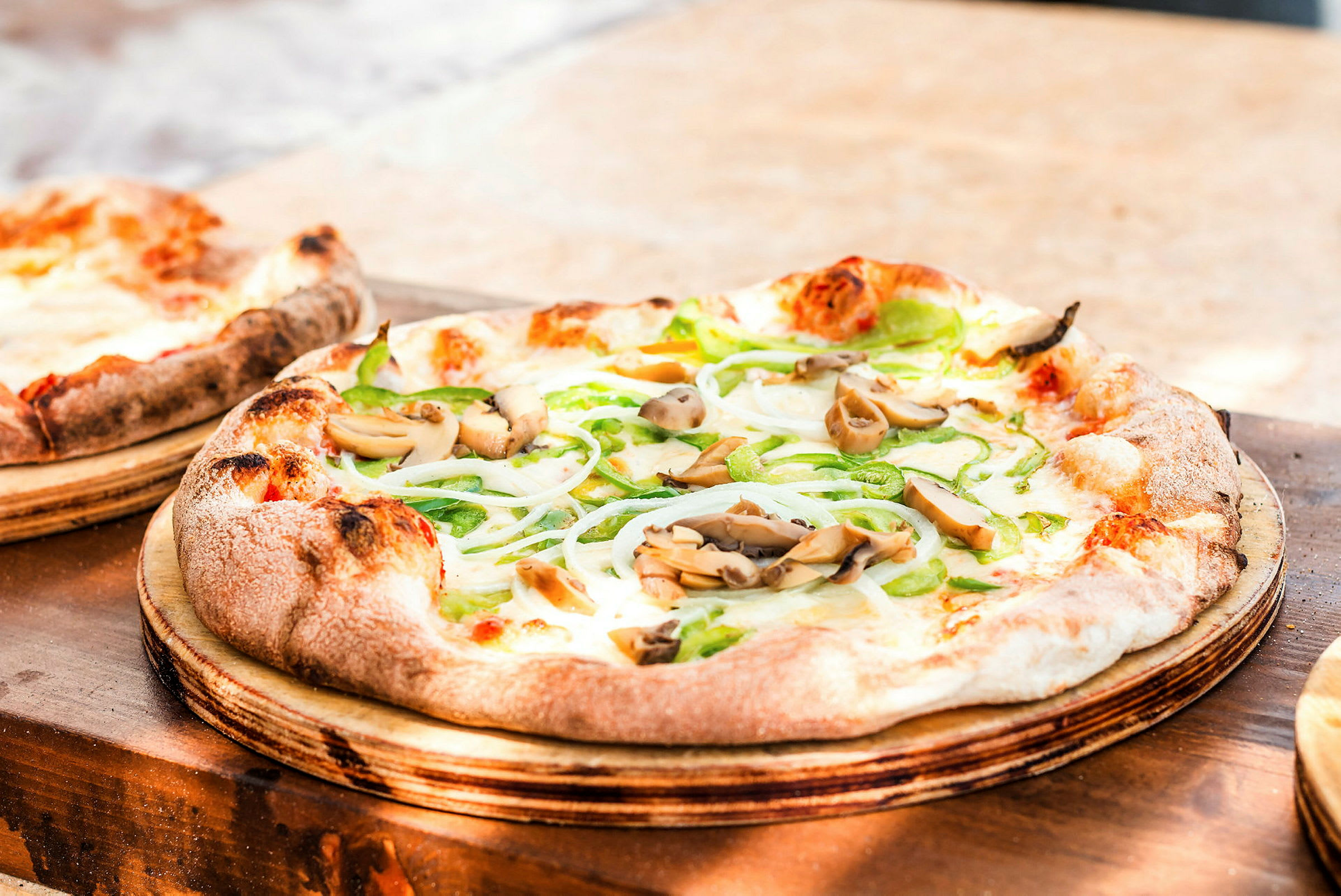 Lähikuva pizzastaan, jossa on vihanneksia ja sieniä, tarjoillaan puutarjottimella. (Tekoälyn luoma teksti)