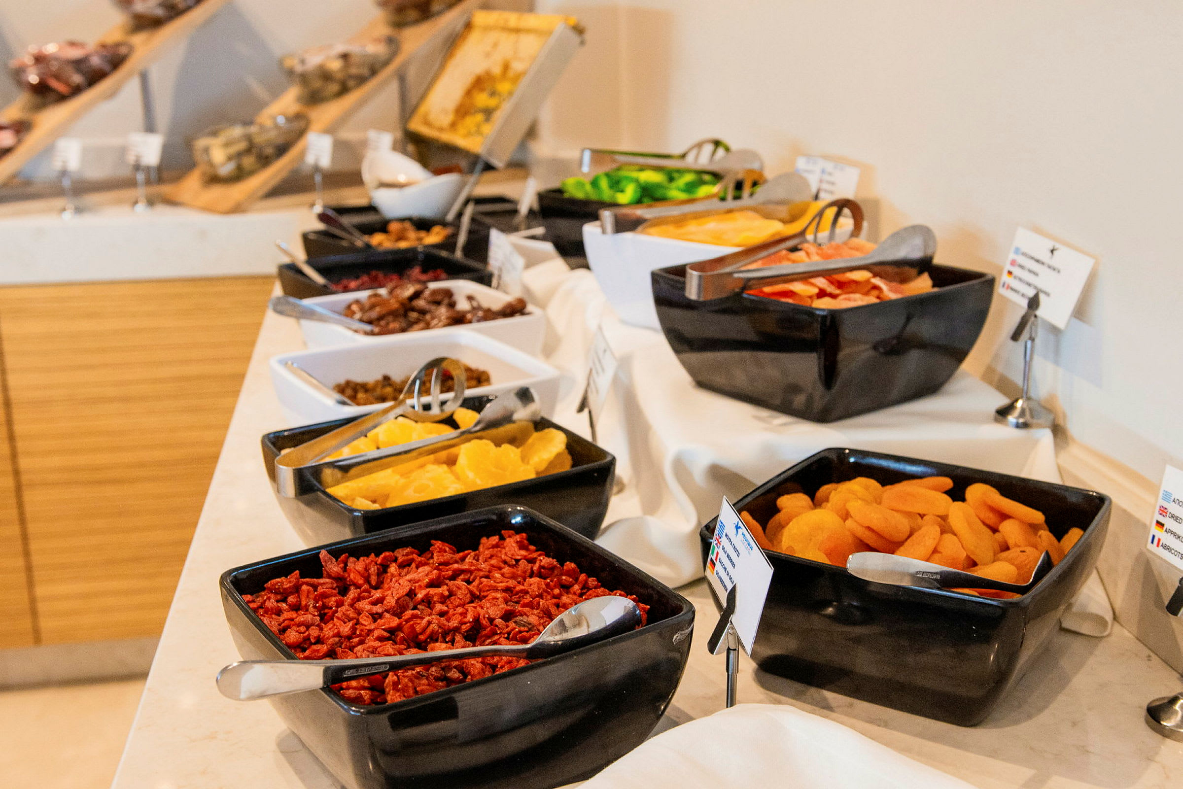 Buffet, jossa on erilaisia kuivattuja hedelmiä ja tuoretuotteita mustissa ja valkoisissa kulhoissa katetulla pöydällä. (Tekoälyn luoma teksti)