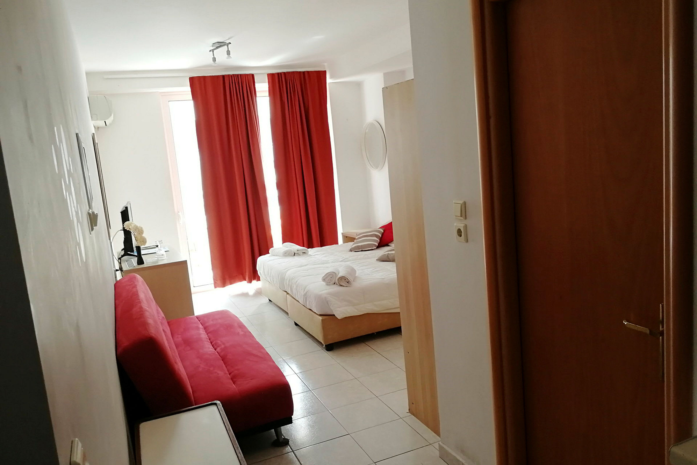 Hotellihuone, jossa on pedattu sänky, punaiset verhot ja punainen sohva. (Tekoälyn luoma teksti)