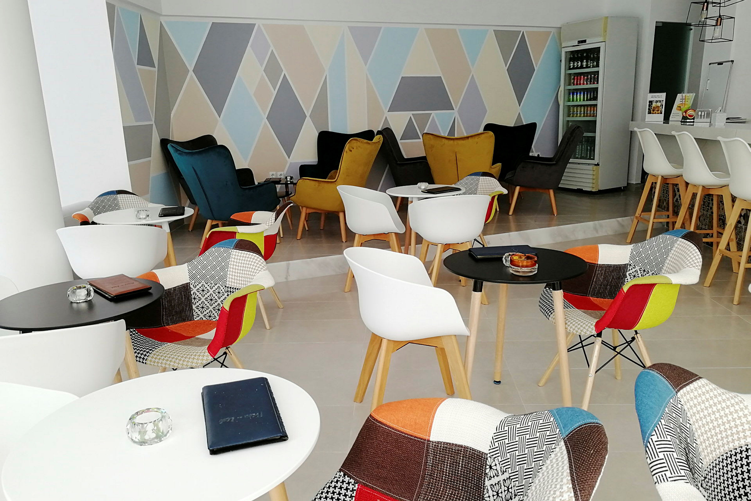 Moderni lounge värikkäillä tuoleilla ja geometriset kuviot seinällä. (Tekoälyn luoma teksti)