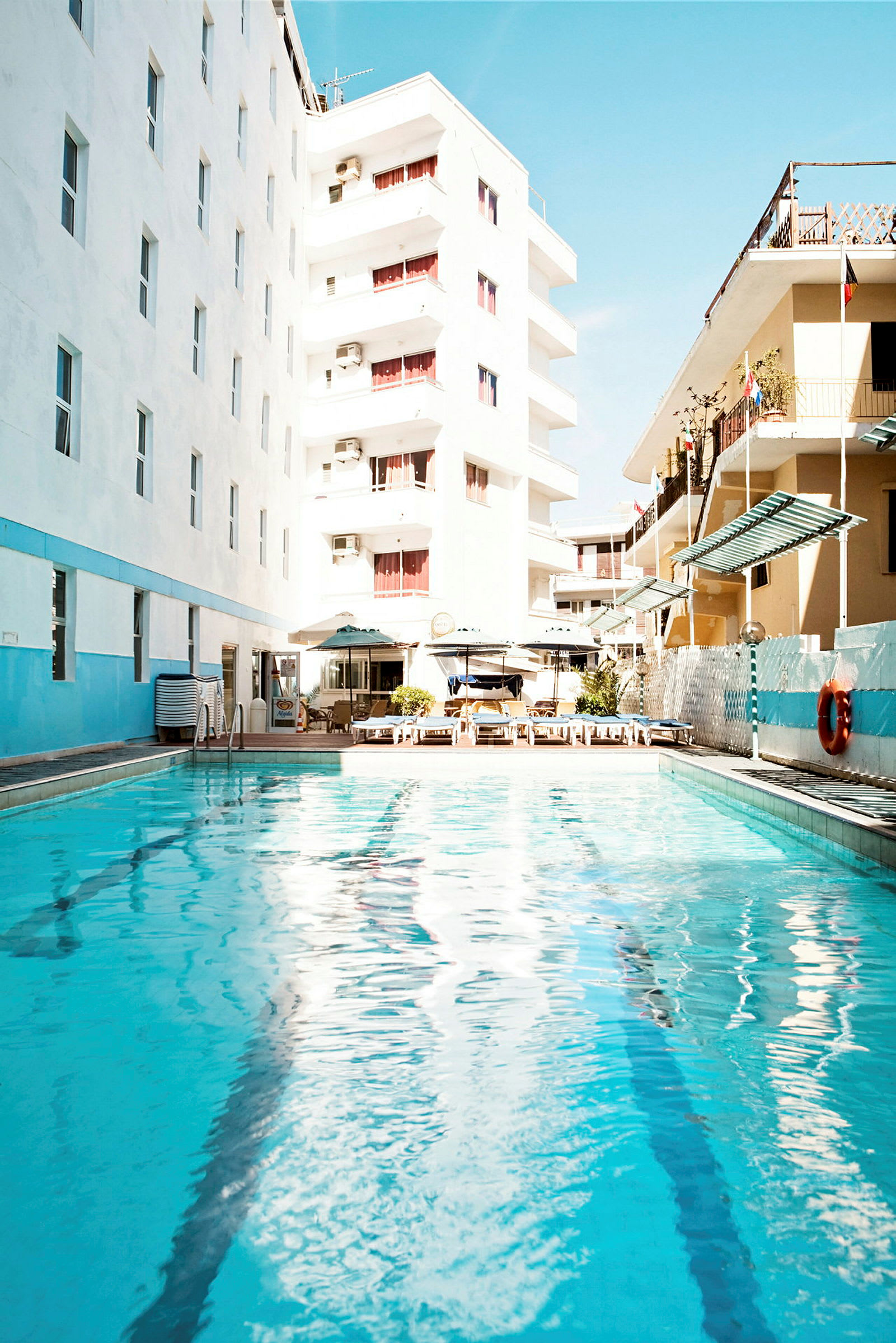 Ulkouima-allas, jota ympäröivät hotellirakennukset ja aurinkotuolit. (Tekoälyn luoma teksti)