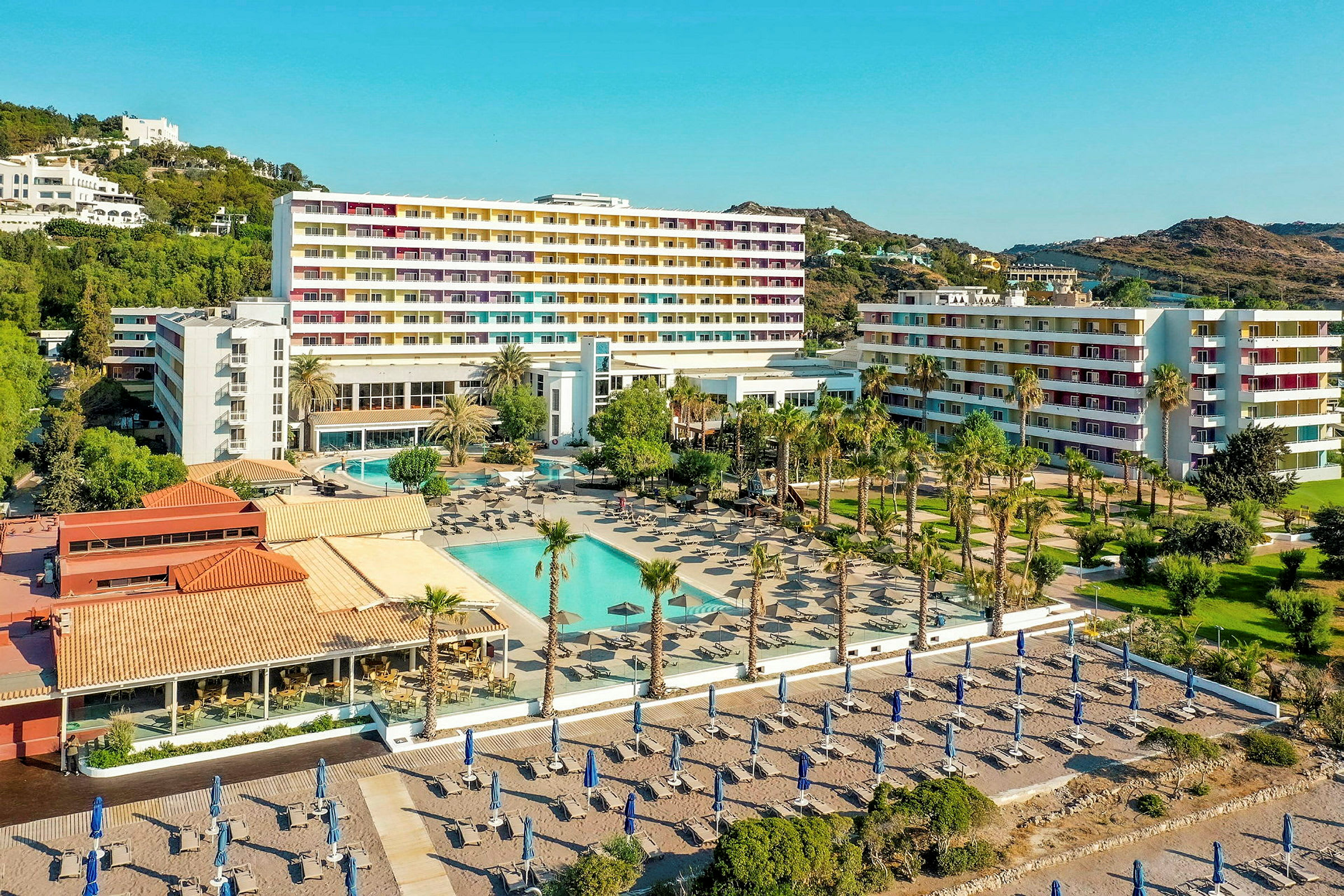 Hotellialue, jossa uima-allas, aurinkotuoleja ja hiekkaranta taustalla. (Tekoälyn luoma teksti)