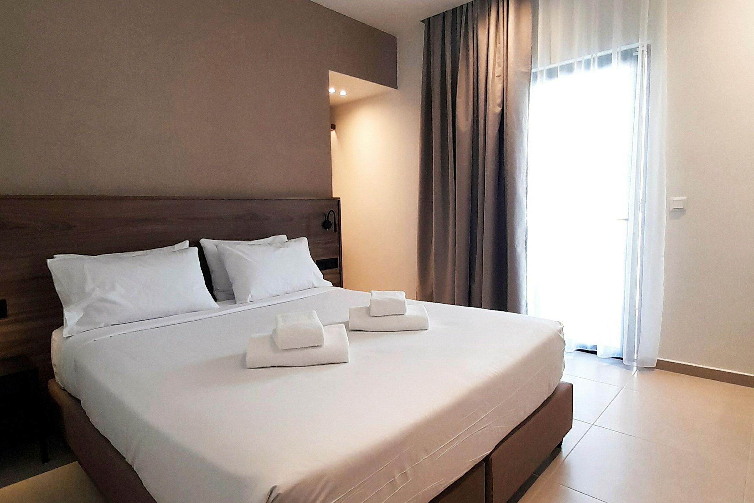 Hotellihuone, jossa on parivuode ja valkoiset lakanat, sekä sängylle asetetut taitetut pyyhkeet. (Tekoälyn luoma teksti)