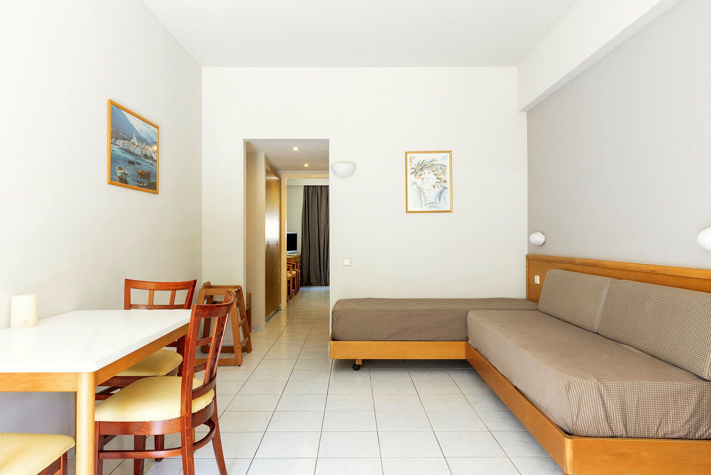 Kuvassa hotellihuone, jossa on pöytä, tuoleja, sohva ja näkymä käytävälle. (Tekoälyn luoma teksti)