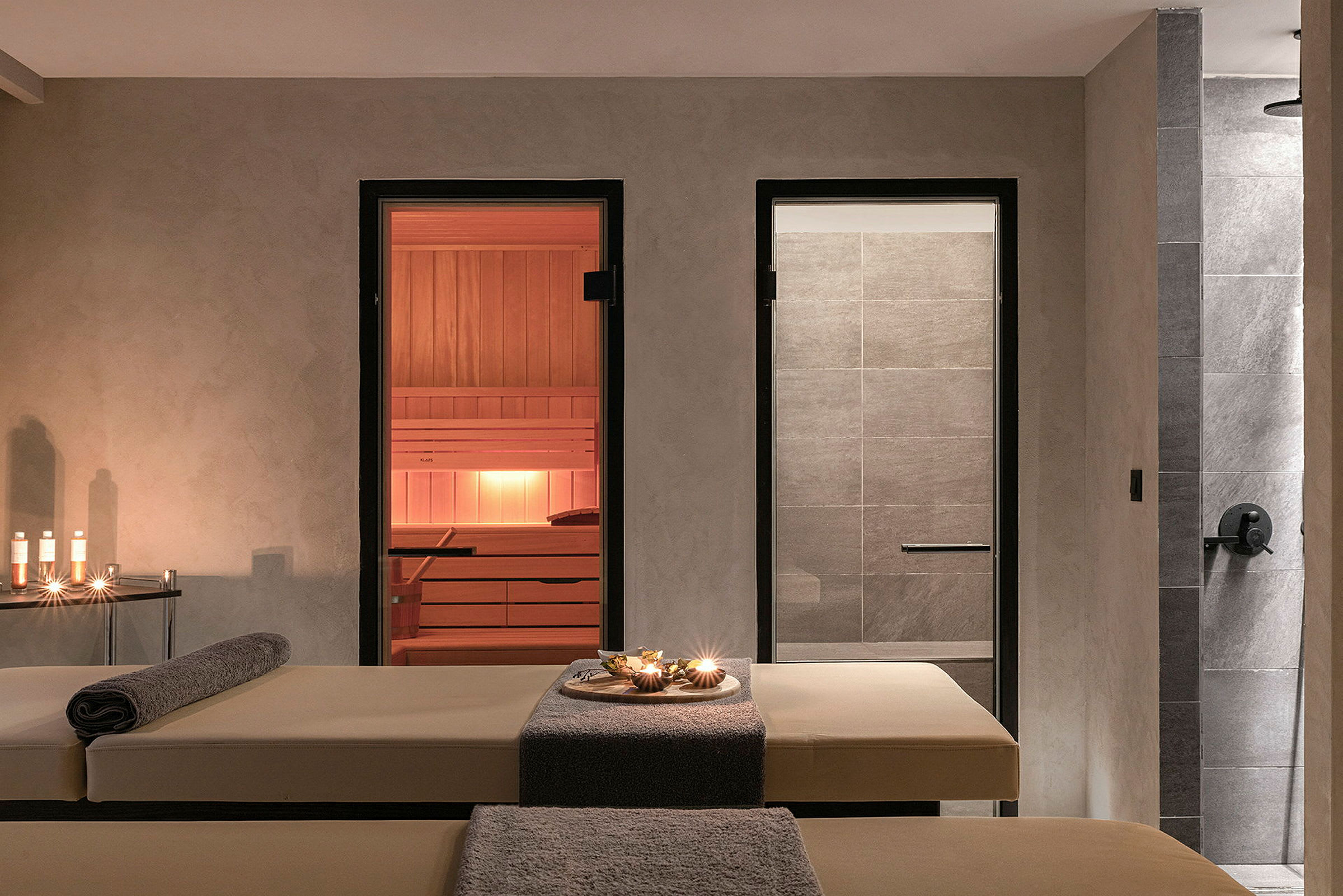 Kuva spa-huoneesta, jossa on hierontapöydät, kynttilöitä ja sauna. (Tekoälyn luoma teksti)