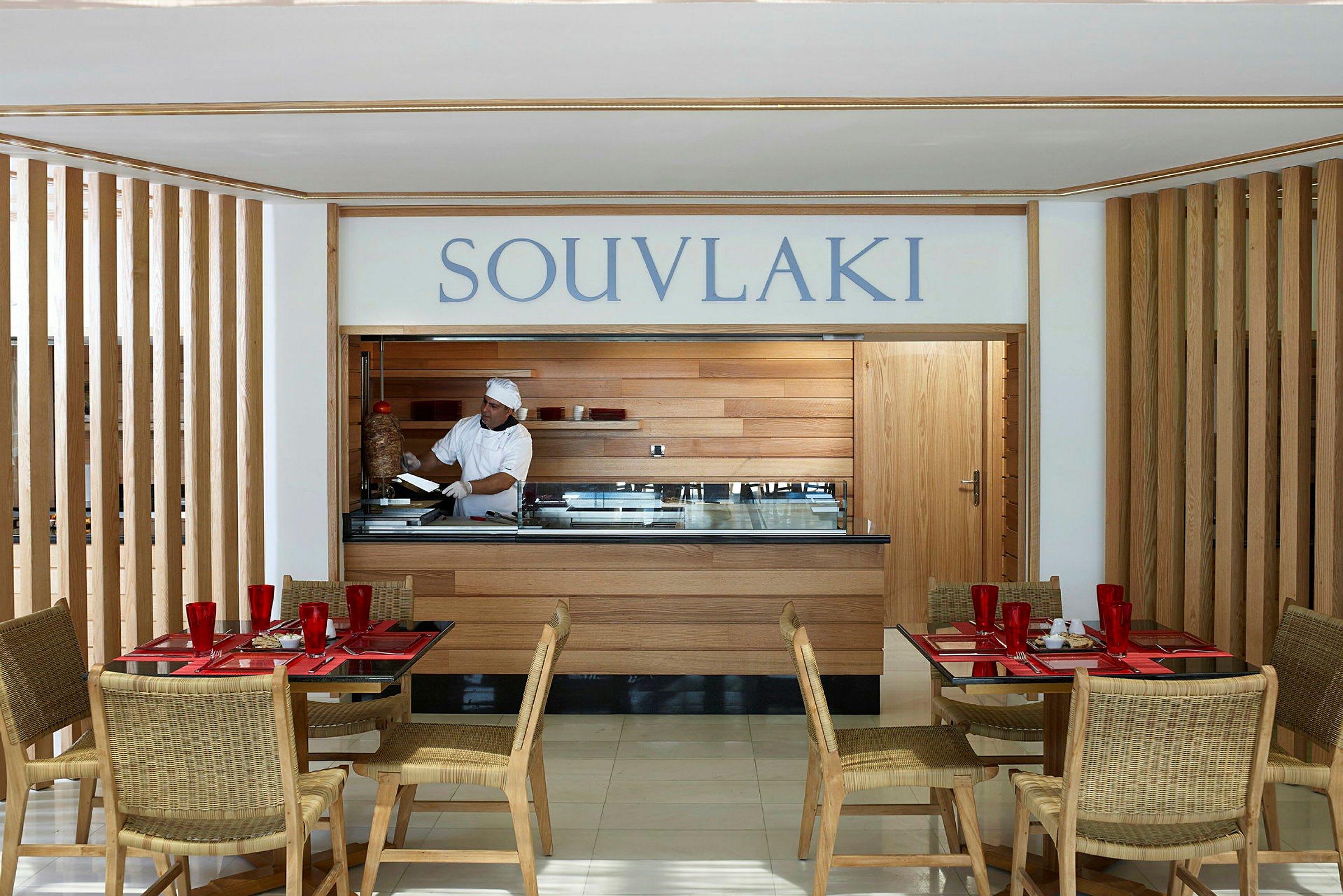 Ravintola, jossa tarjoillaan souvlakia. Etualalla on pöytiä ja tuoleja. (Tekoälyn luoma teksti)