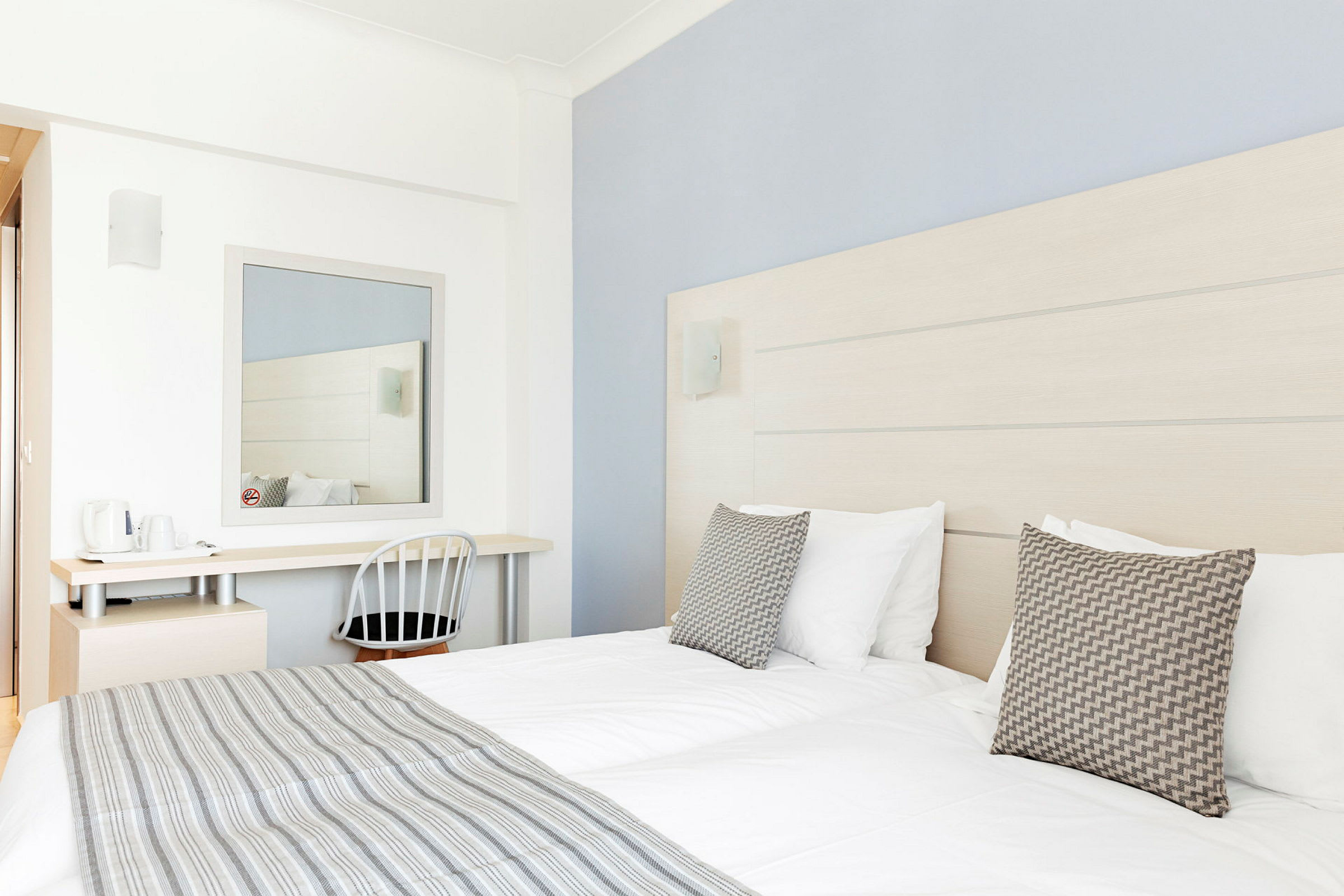 Hotellihuone, jossa kaksi sänkyä, kirjoituspöytä ja peili. (Tekoälyn luoma teksti)