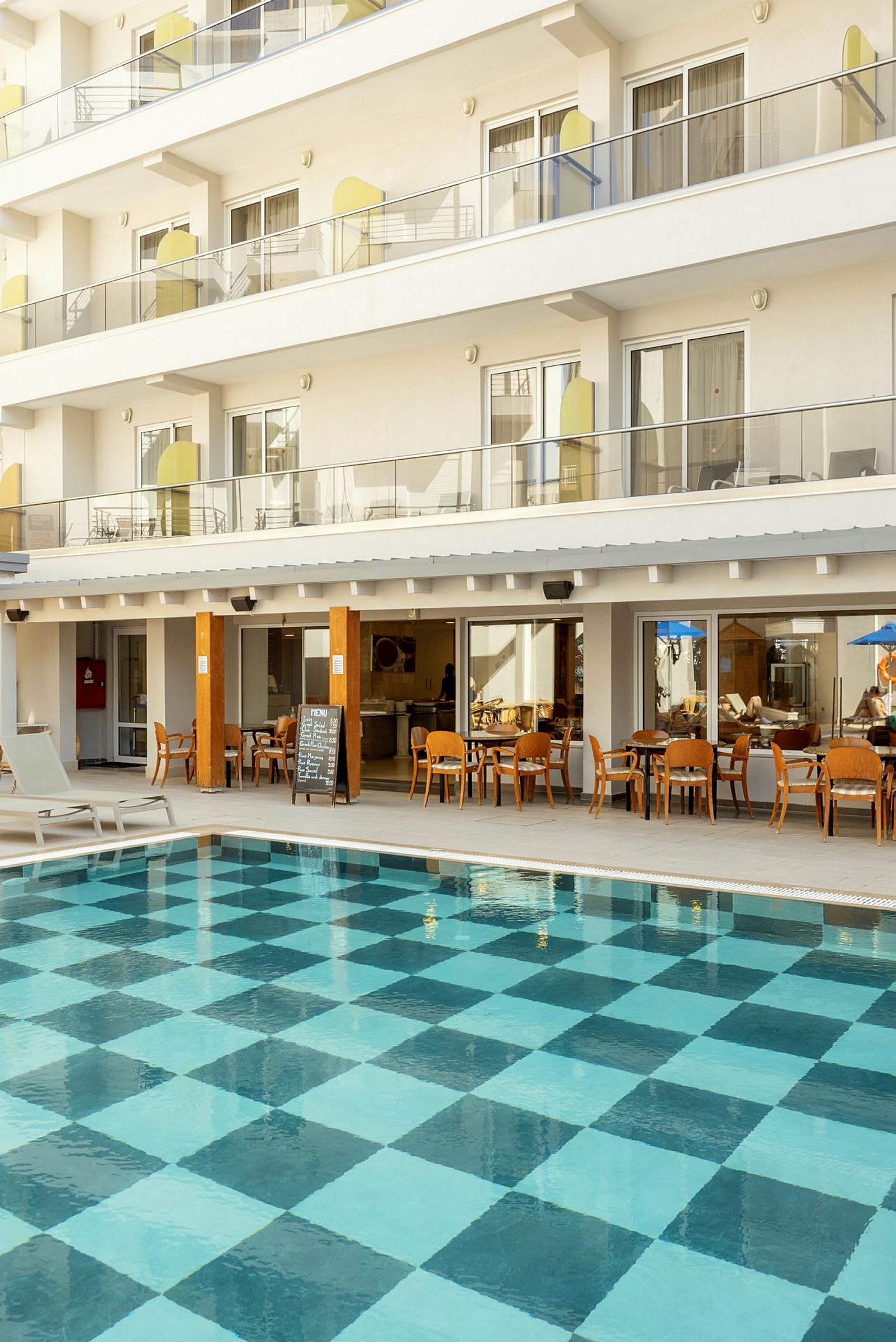 Ulkouima-allas, jonka pohjassa ruutukuvio, hotellirakennuksen parvekkeiden ja ravintolan edessä. (Tekoälyn luoma teksti)