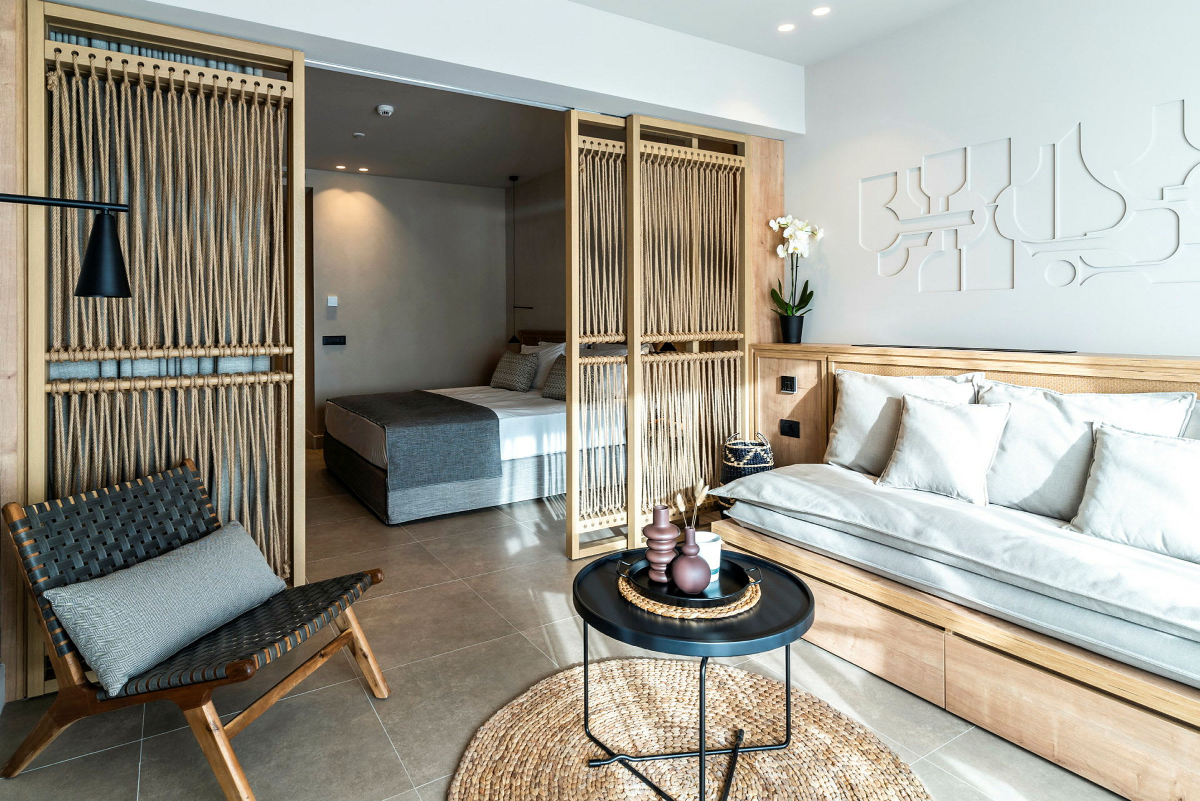 Moderni hotellihuone, jossa istuinalue ja erillinen makuutila. (Tekoälyn luoma teksti)