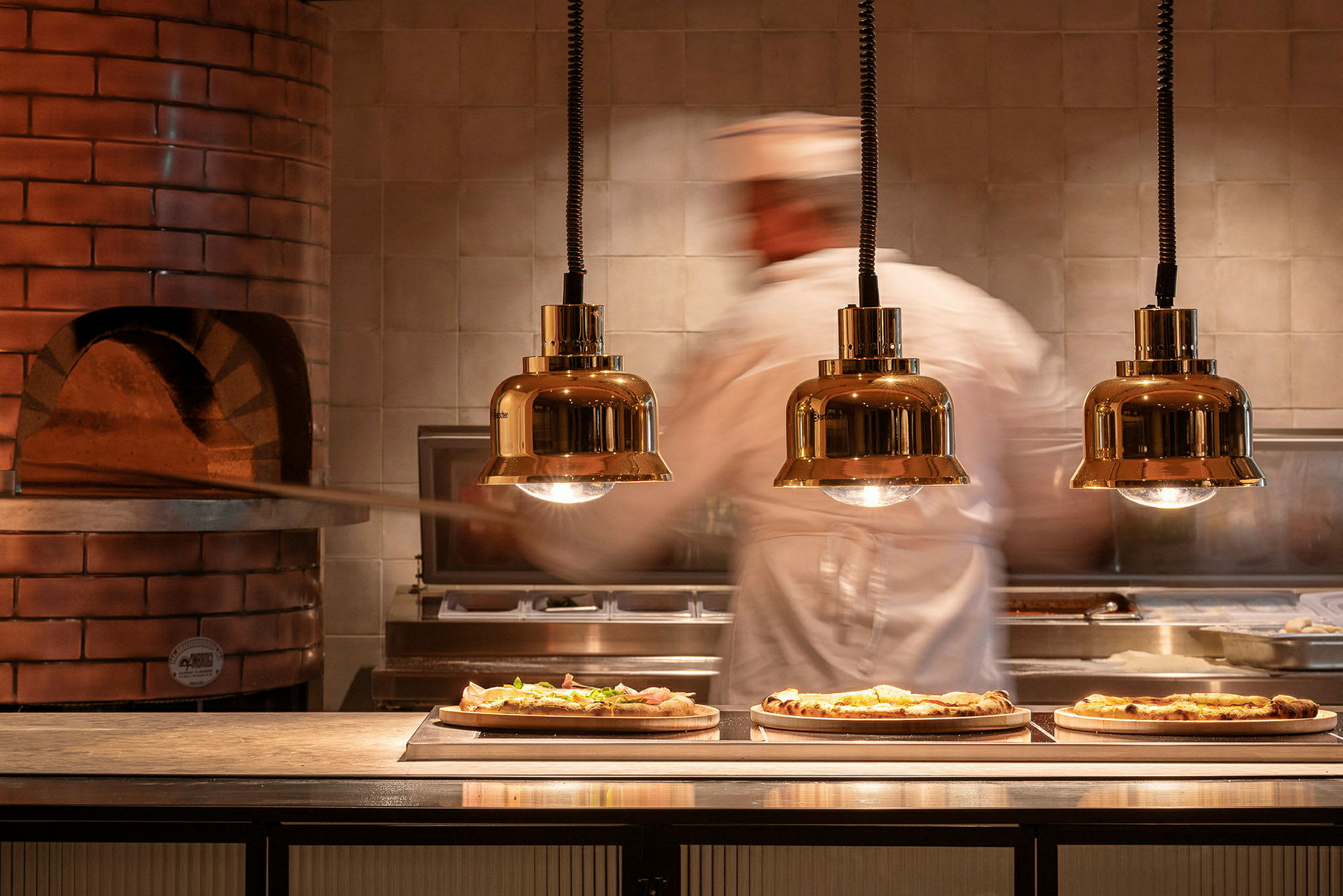 Pizzaleipuri työskentelee uunin äärellä, jossa kolme valmista pizzaa on tarjoilupöydällä. (Tekoälyn luoma teksti)