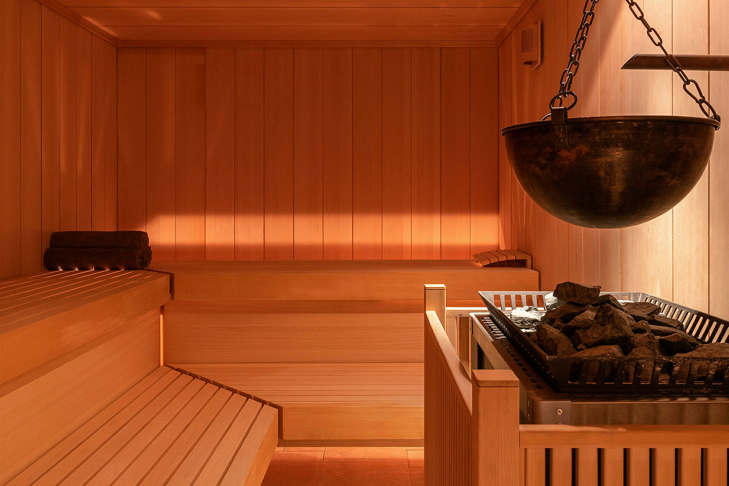 Sauna, jossa on puupenkit ja lämmityslaite kivillä. (Tekoälyn luoma teksti)