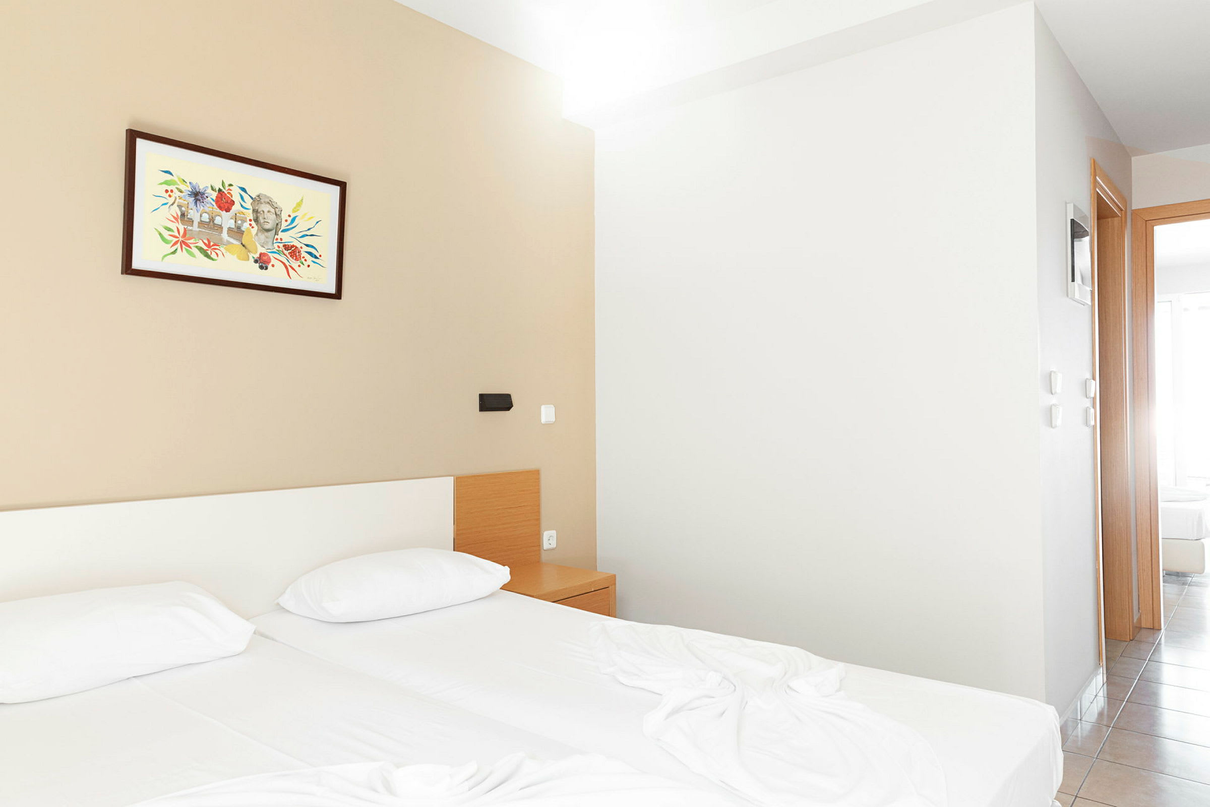 Hotellihuone, jossa on kaksi vuodetta, yöpöytä ja maalaus seinällä. (Tekoälyn luoma teksti)