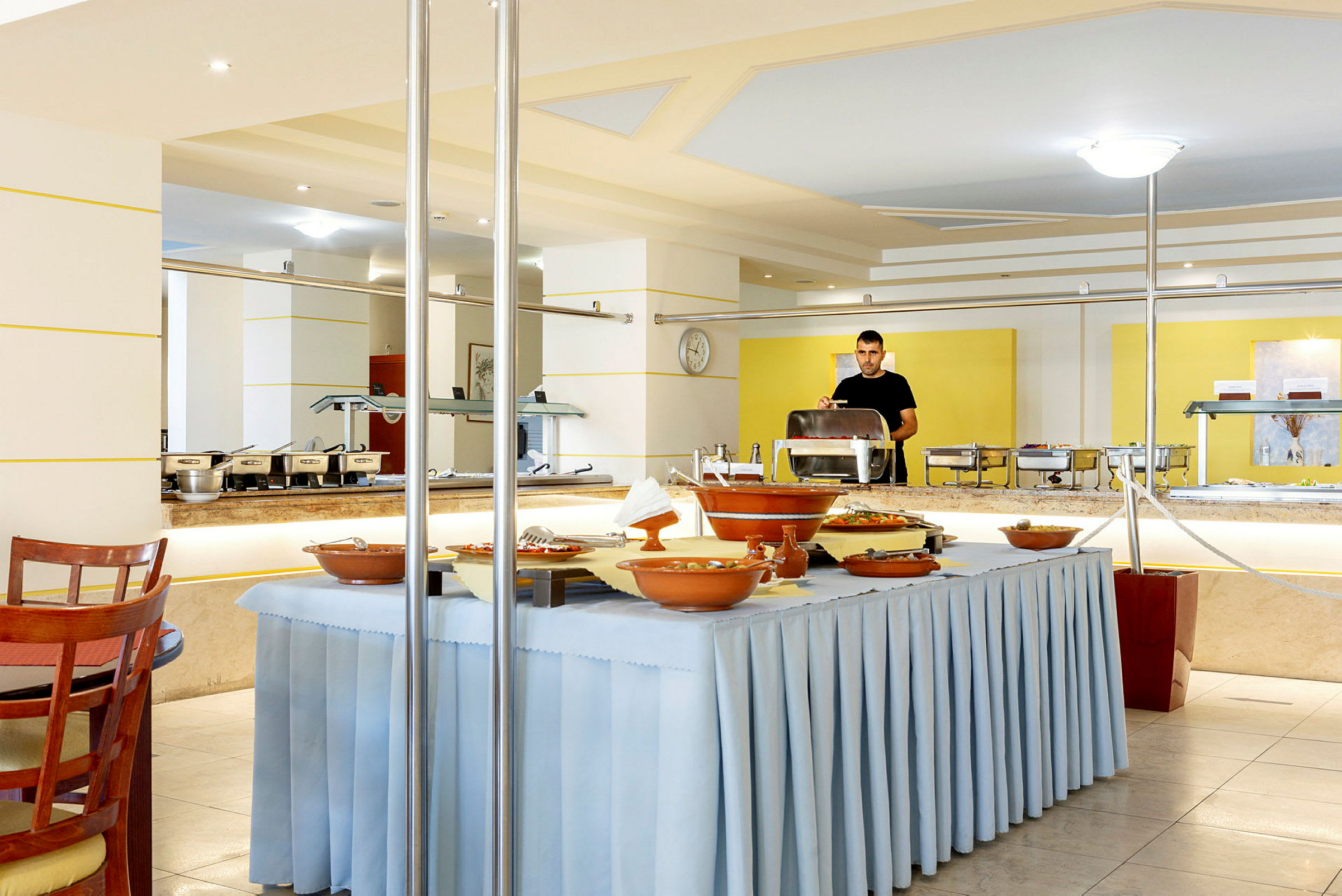 Buffet vaaleassa ravintolassa, jossa on keltainen ja valkoinen sisustus. (Tekoälyn luoma teksti)