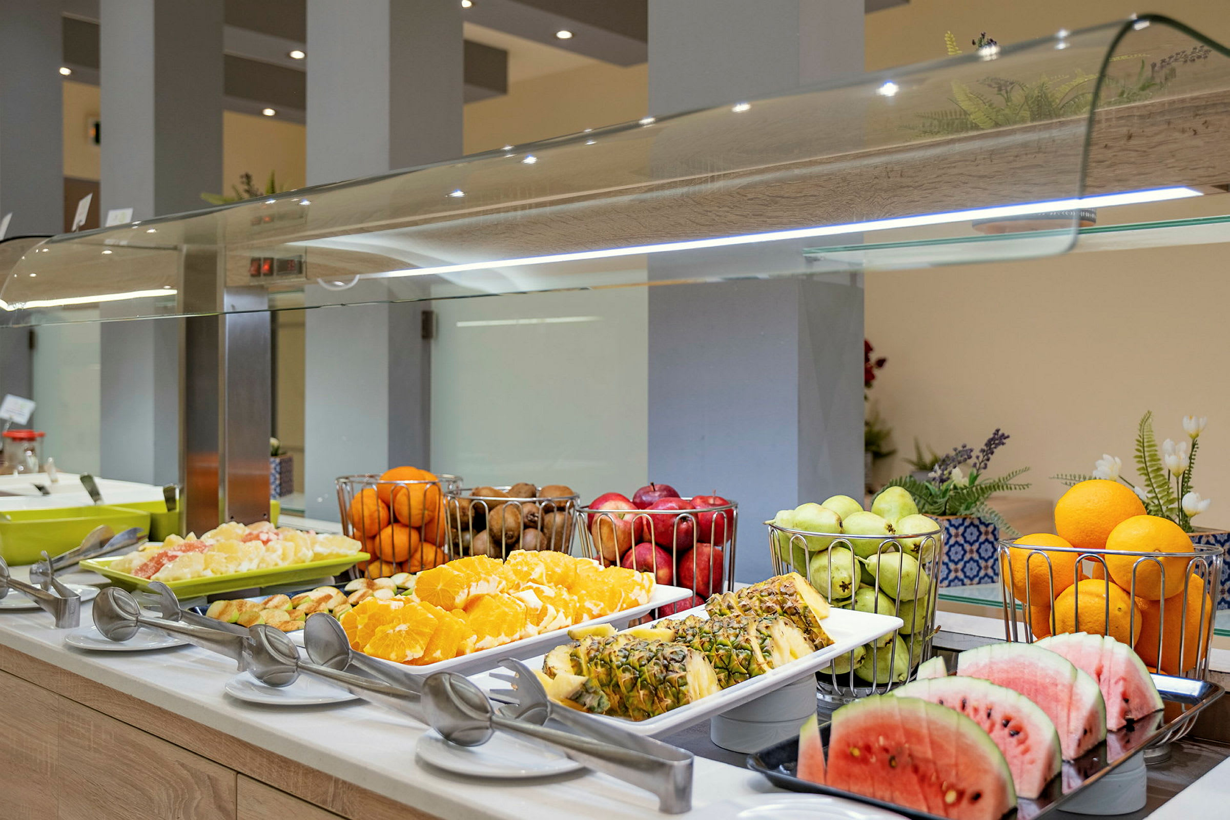 Buffet, jossa on erilaisia hedelmiä, kuten viipaloitua vesimelonia ja ananasta, appelsiineja ja rypäleitä. (Tekoälyn luoma teksti)