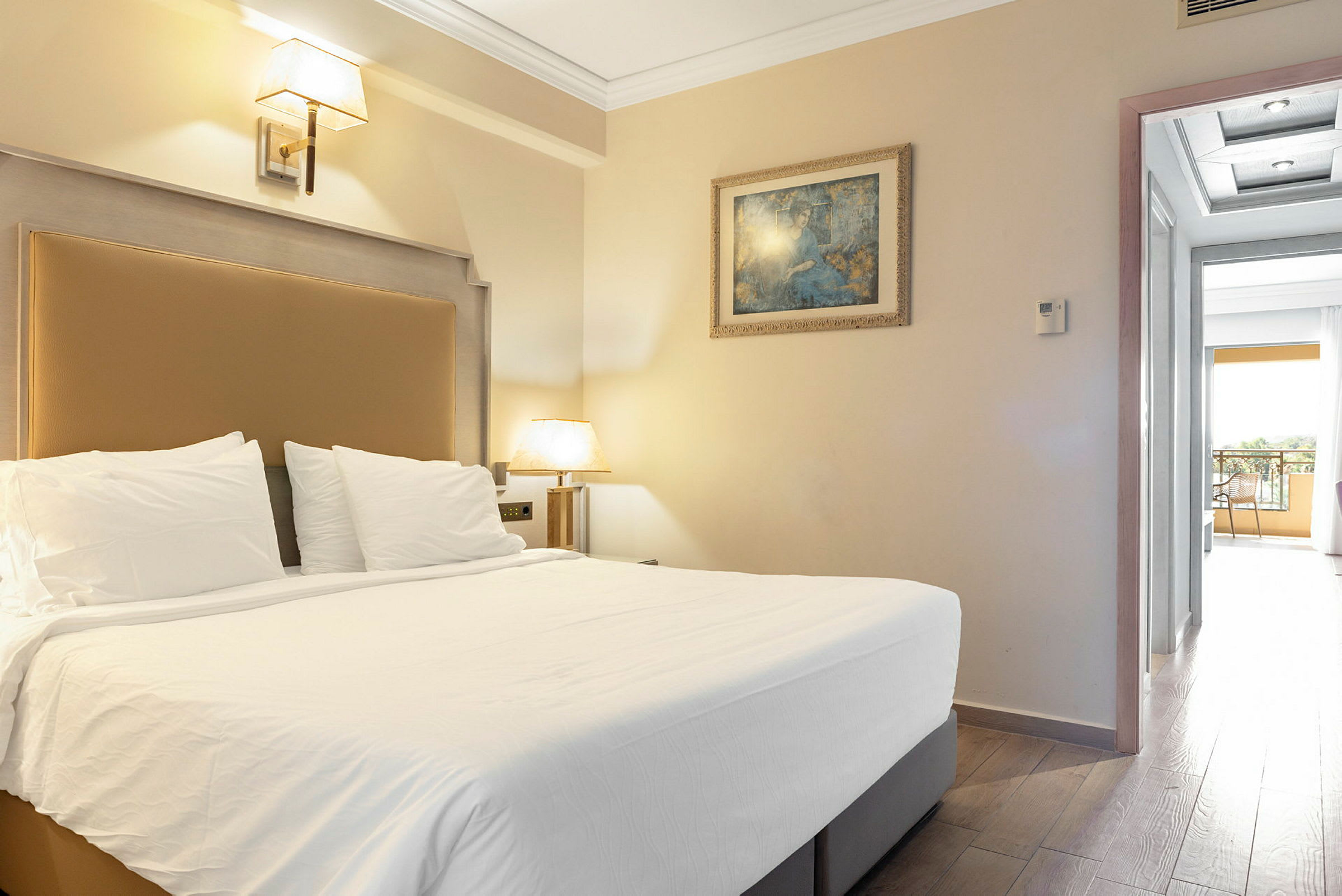 Kuva hotellihuoneesta, jossa on parisänky, seinävalaisin, maalaus ja avaus parvekkeelle. (Tekoälyn luoma teksti)