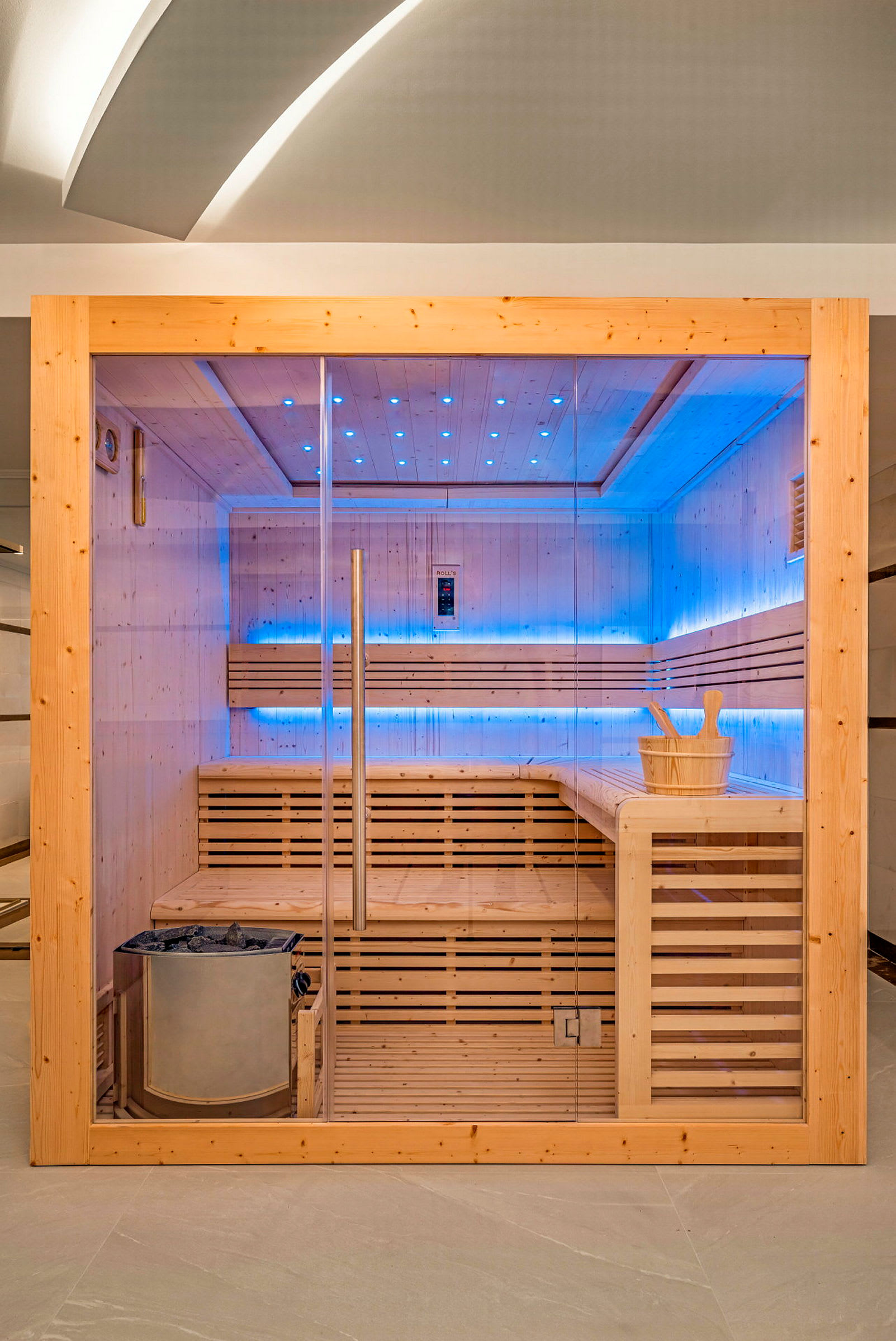 Sauna, jossa puupaneelit, lasiovi ja sininen valaistus. (Tekoälyn luoma teksti)