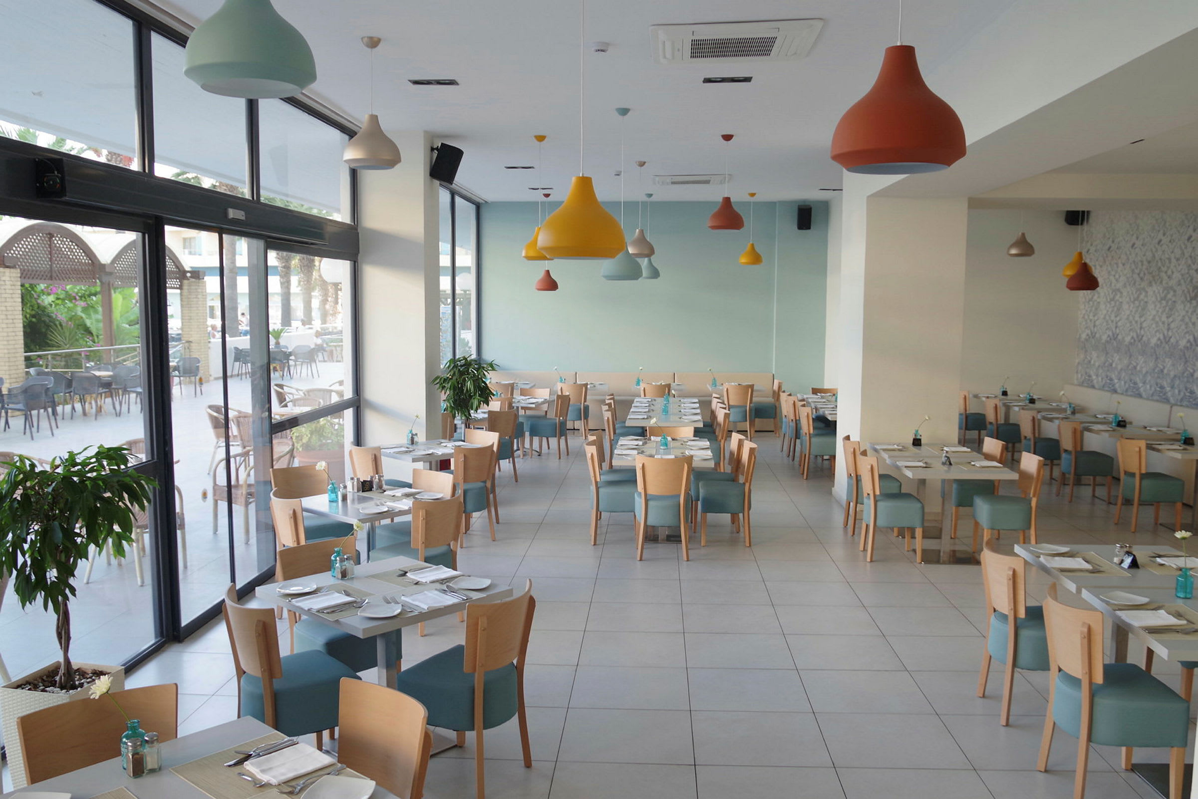Valoisa ja moderni ravintola, jossa pöydät ja tuolit ovat aseteltuina. (Tekoälyn luoma teksti)