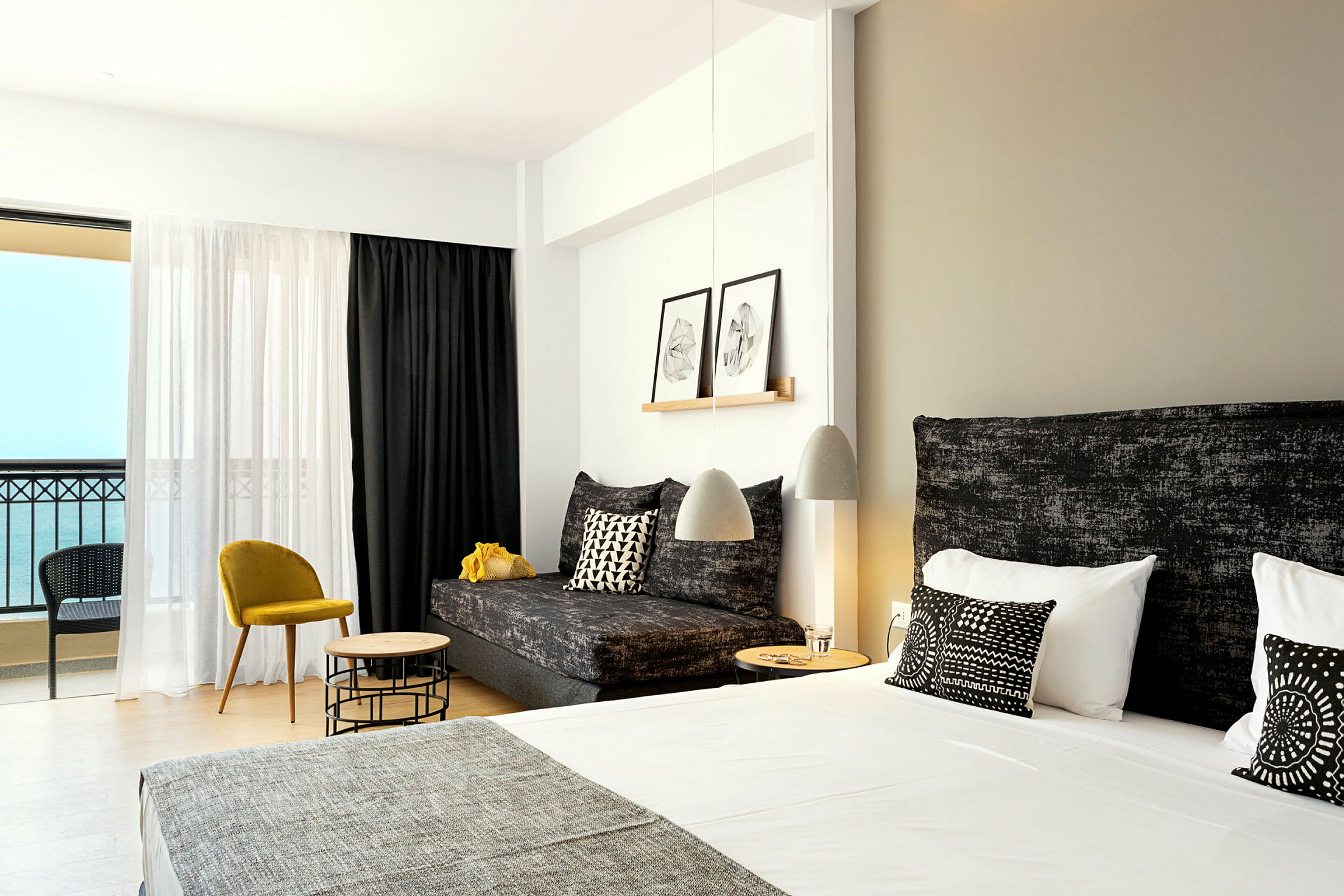 Valoisia ja moderneja hotellihuoneita, joissa parivuode ja oleskelutilan kalusteet. (Tekoälyn luoma teksti)