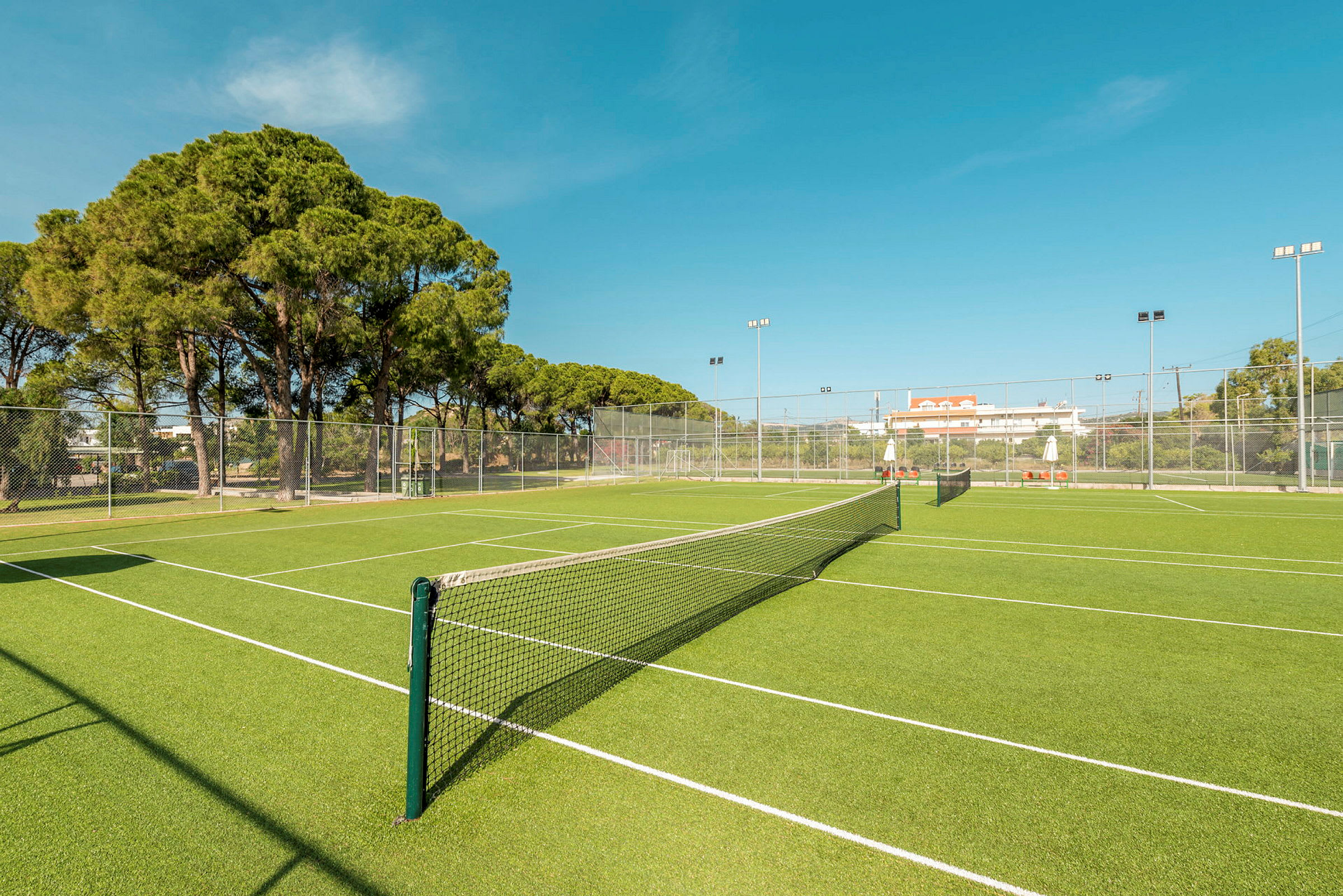 Vihreä tenniskenttä verkolla ja ympäröivällä aidalla. (Tekoälyn luoma teksti)