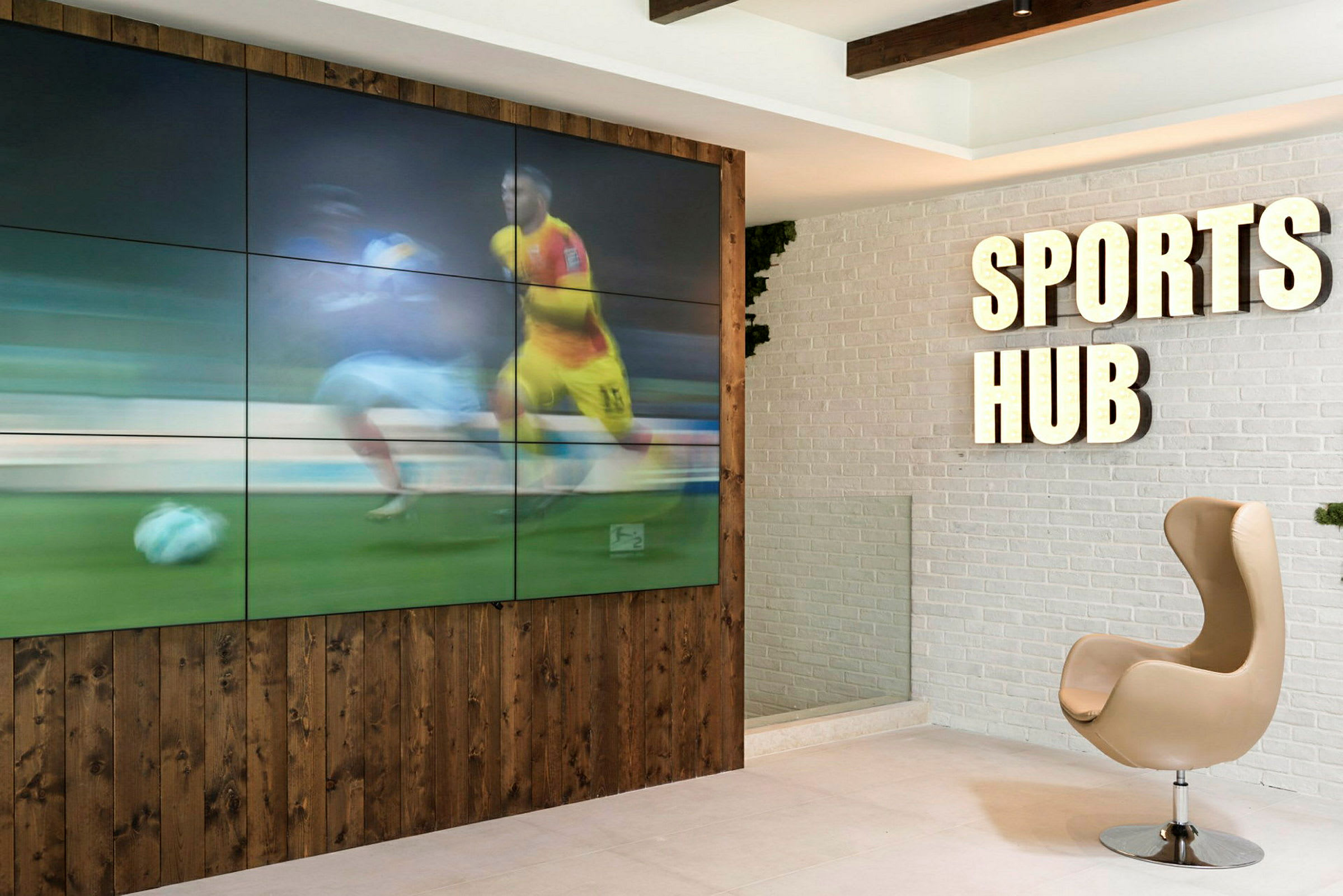 Sisustus kuin Sports Hub -kyltti ja näyttö näyttää urheilua. (Tekoälyn luoma teksti)