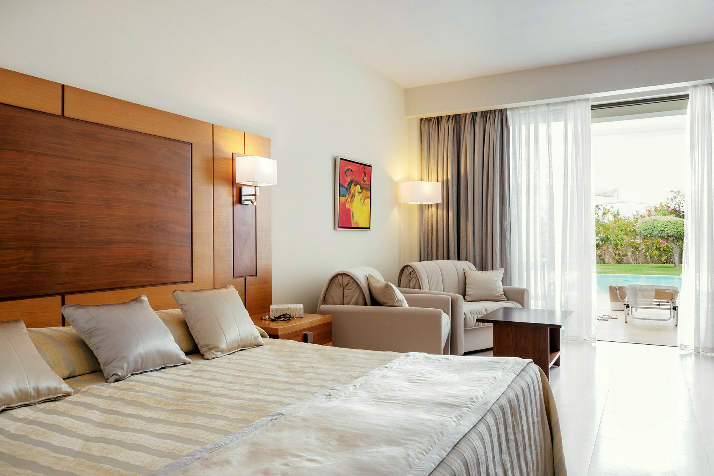Hotellihuone, jossa on parivuode, istuimet ja näkymä ulkouima-altaalle. (Tekoälyn luoma teksti)