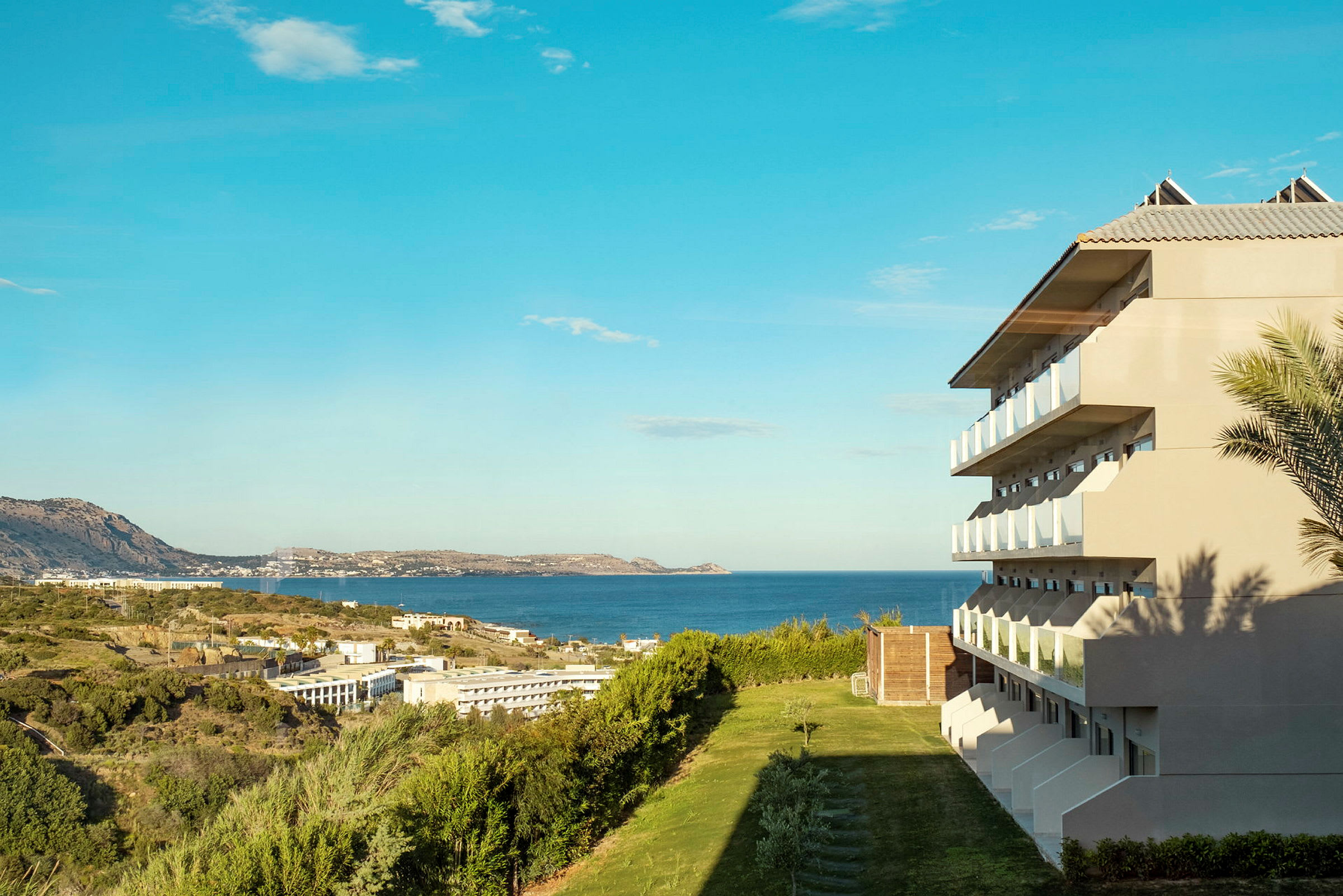 Kuva hotellista, jossa on parvekkeita näköalalla merelle ja viheralueille. (Tekoälyn luoma teksti)