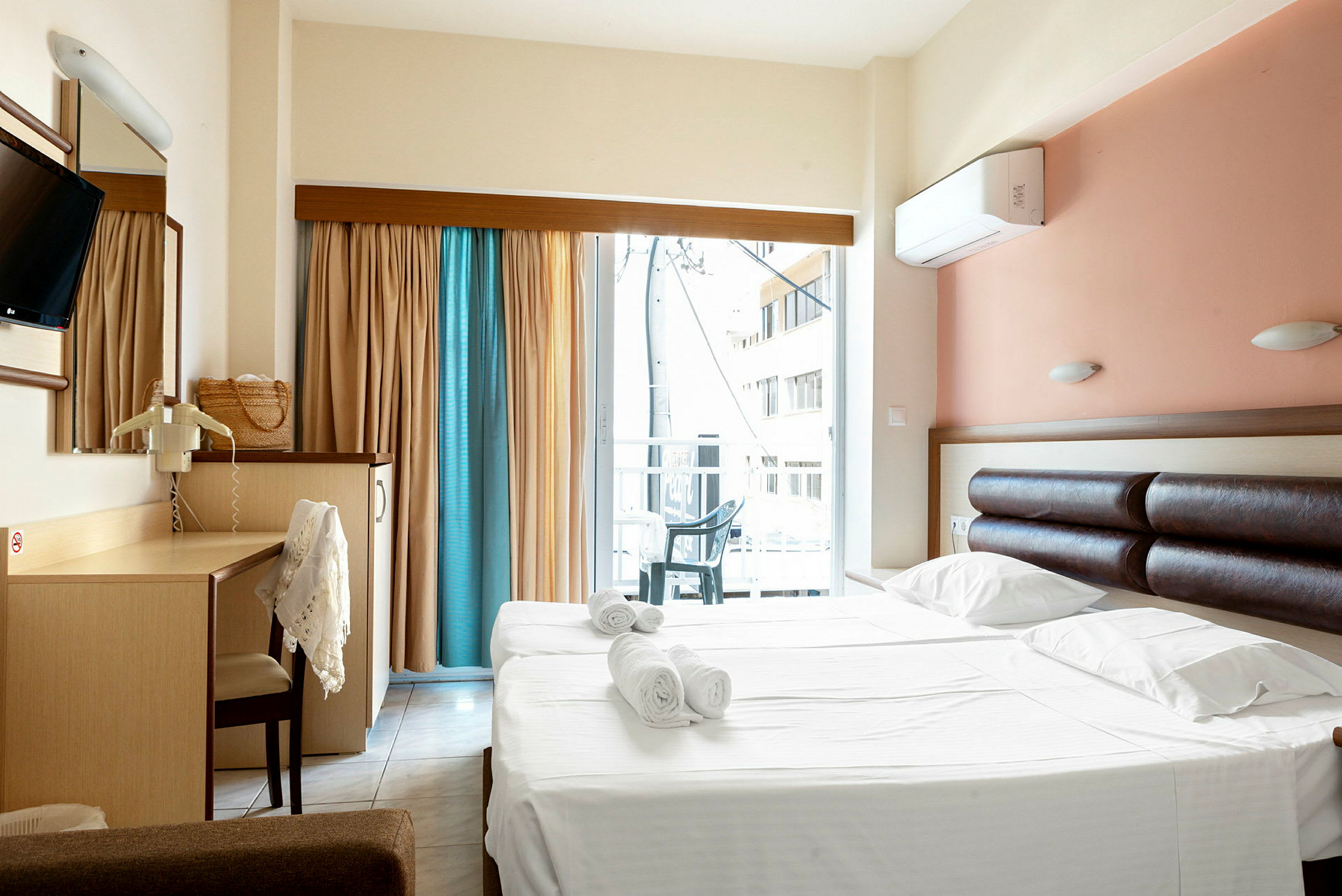Hotellihuone, jossa on parivuode ja kirjoituspöytä sekä parveke ja näkymä. (Tekoälyn luoma teksti)