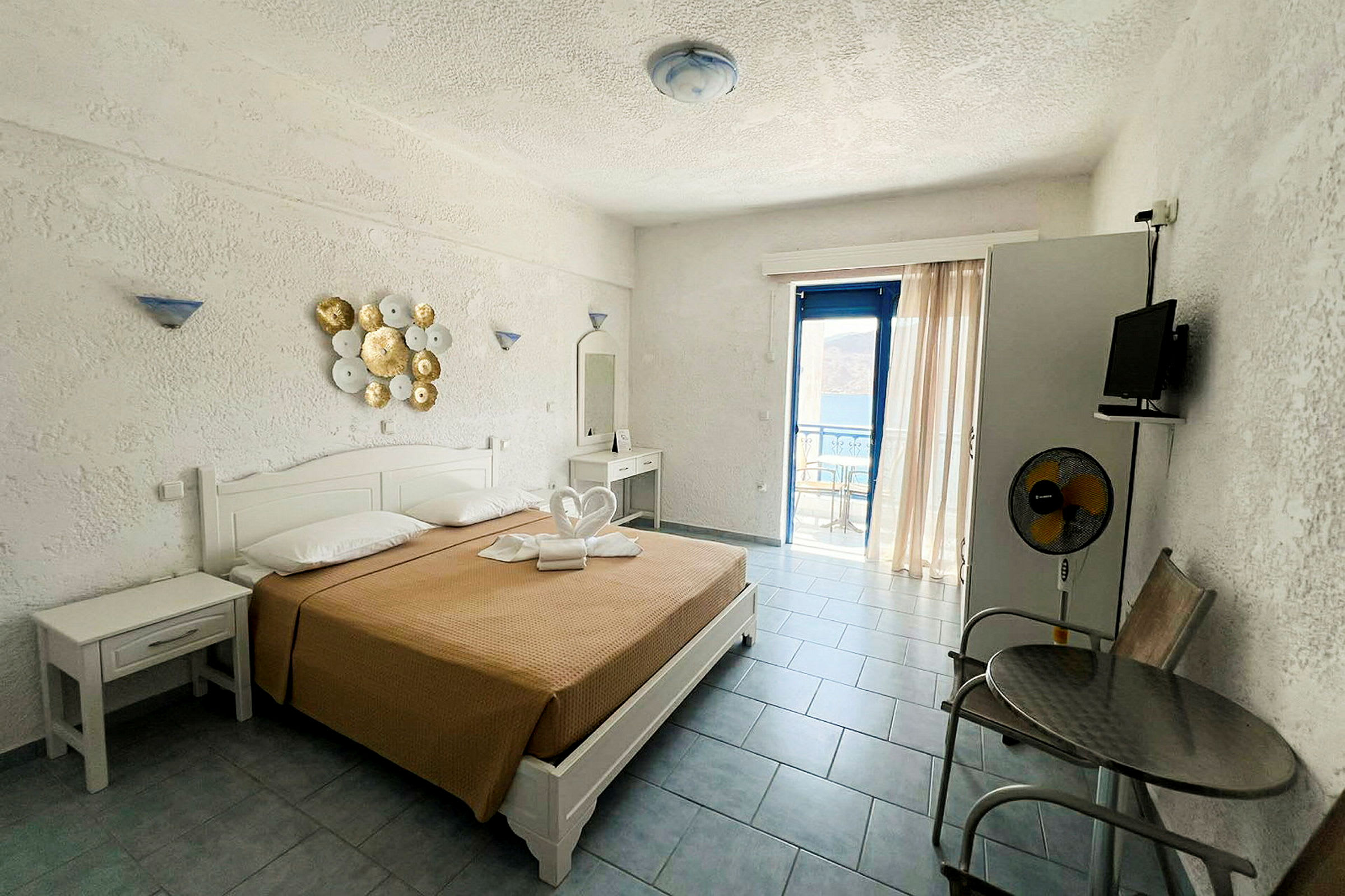 Hotellihuone, jossa on parisänky ja pyyhkeillä koristeltu, ja näkymä lasioven läpi parvekkeelle. (Tekoälyn luoma teksti)