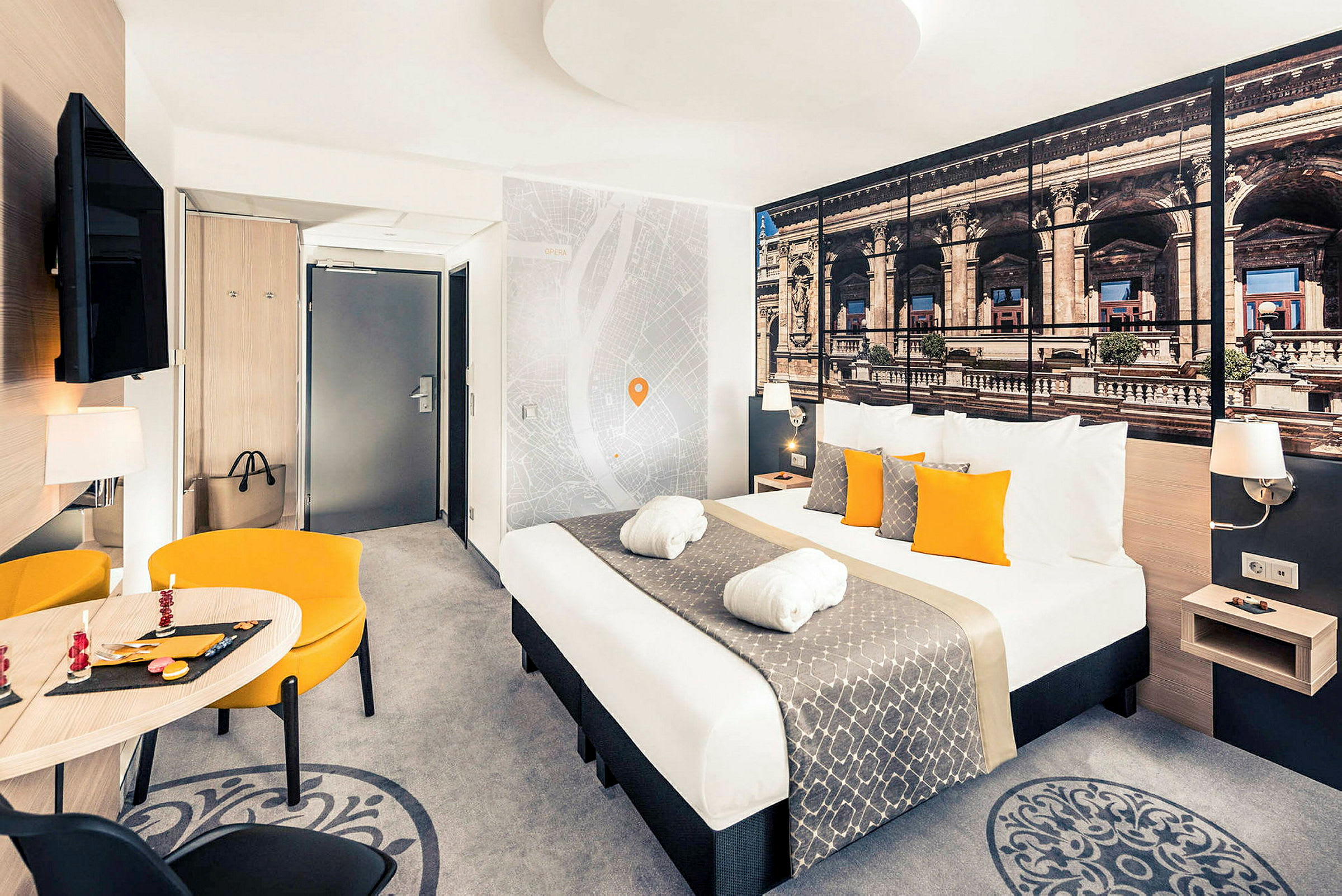 Hotellihuone, jossa on parisänky, ruokailuhuonekalut ja seinäkoristeita. (Tekoälyn luoma teksti)