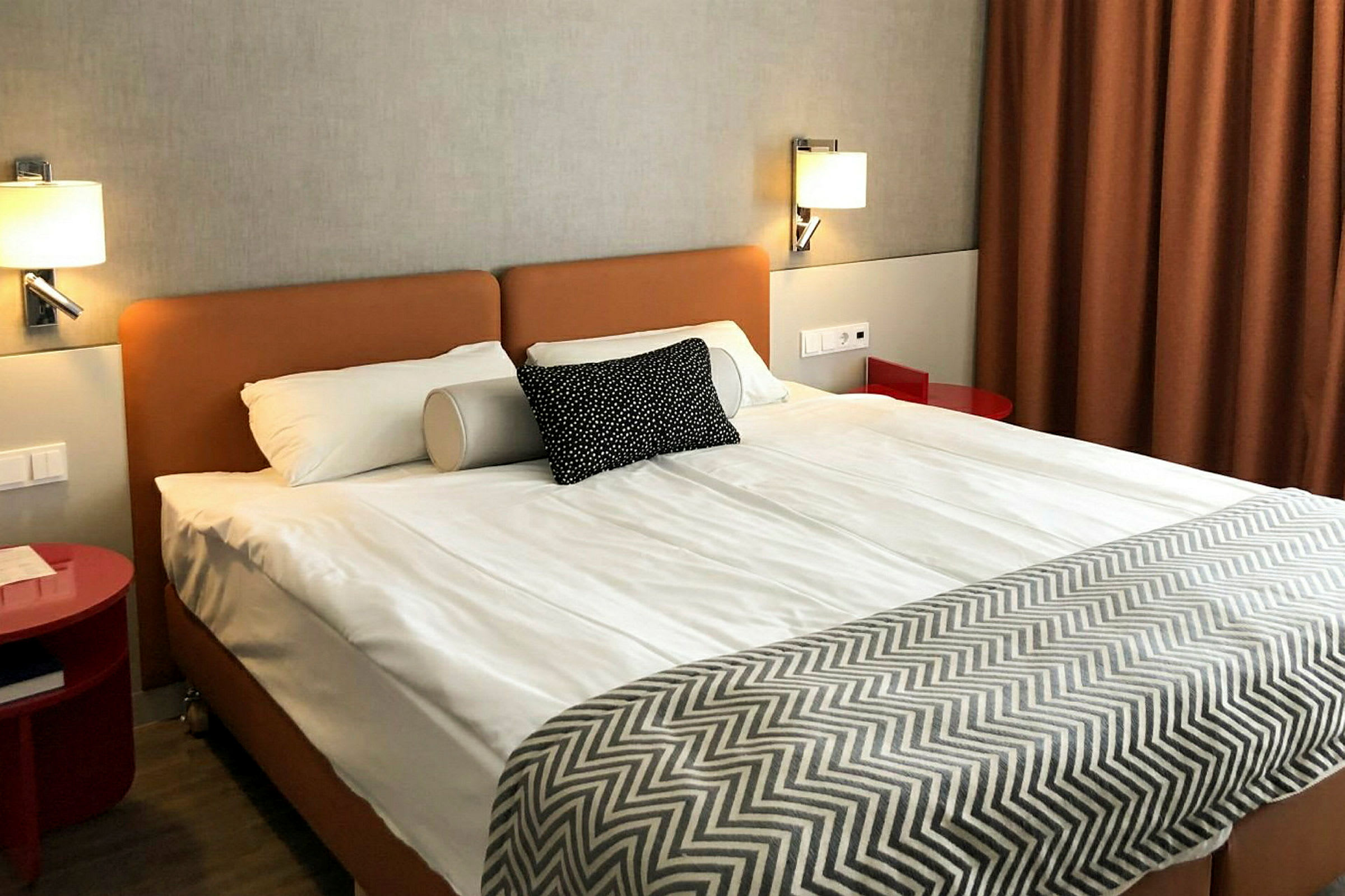 Hotellihuone, jossa parivuode, pieni yöpöytä ja ruskea verho. (Tekoälyn luoma teksti)