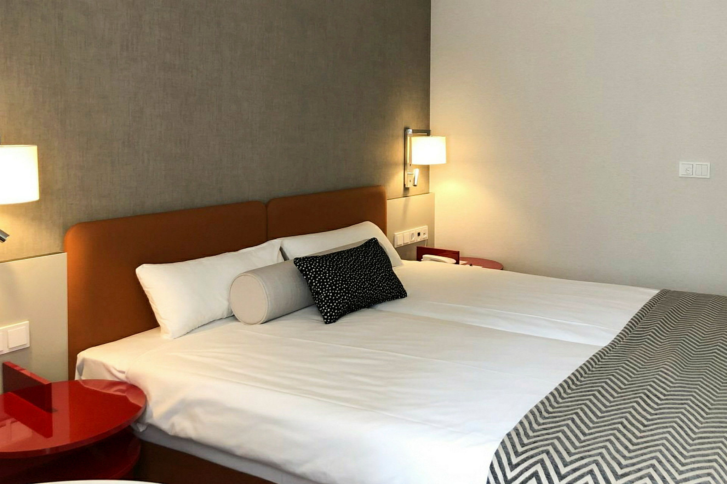 Hotellihuone, jossa on parisänky ja seinälamput valaistuna. (Tekoälyn luoma teksti)
