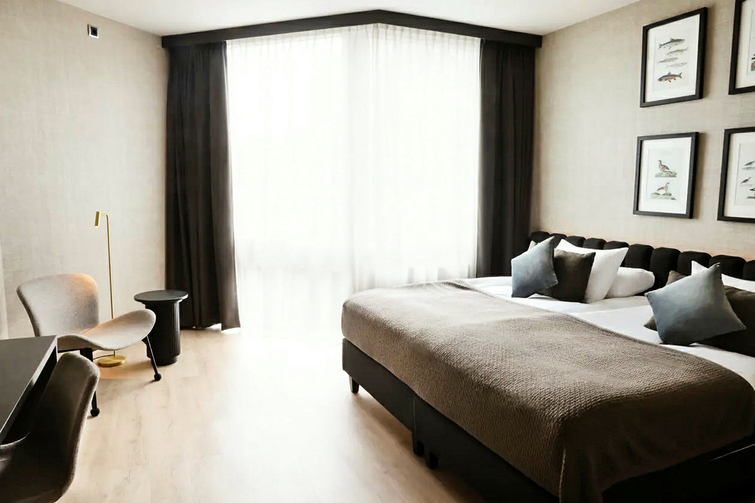 Hotellihuone, jossa on parivuode, istuimia ja suuri ikkuna vaaleilla verhoilla. (Tekoälyn luoma teksti)