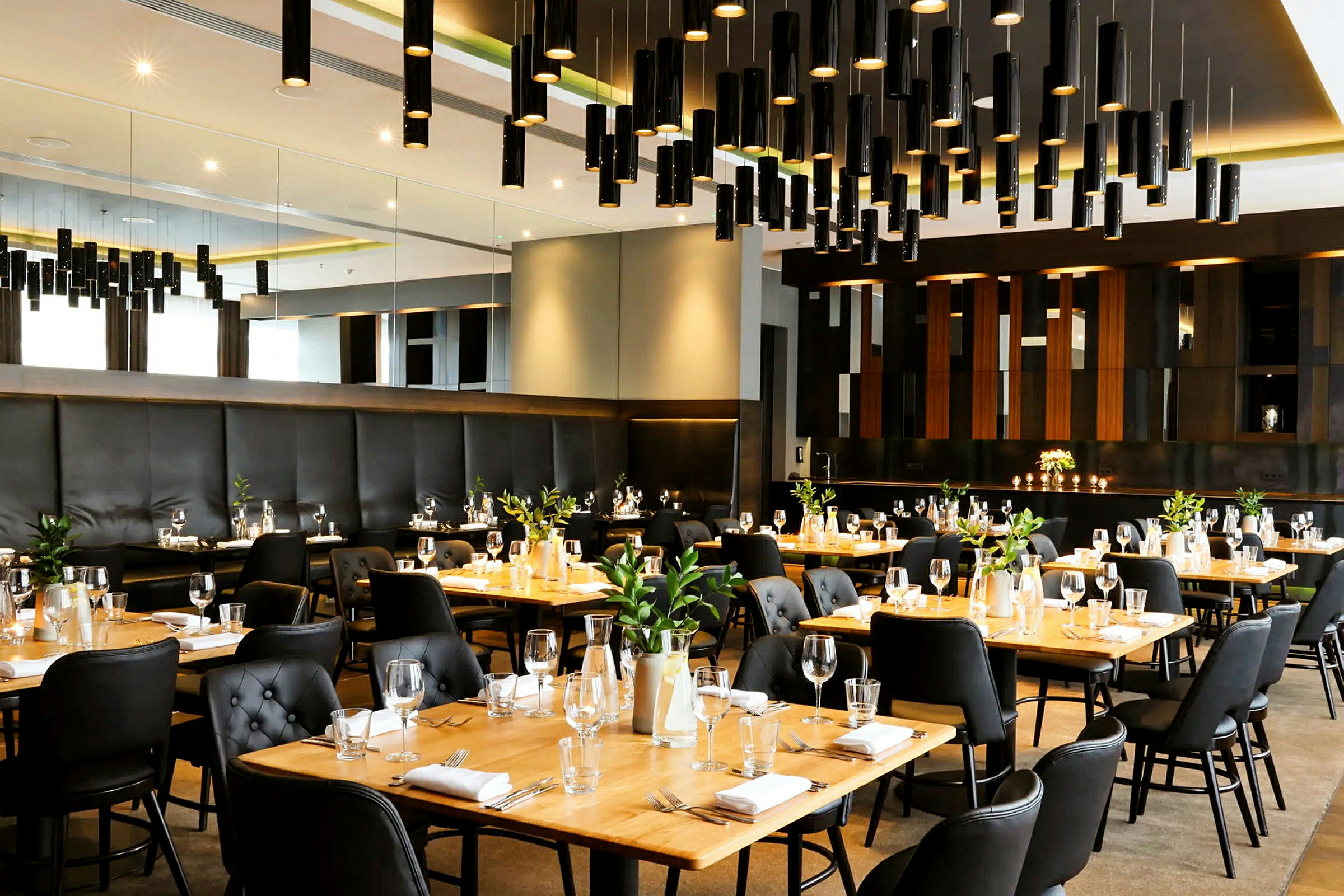 Tyylikäs ravintola, jossa on katettuja pöytiä, mustia tuoleja ja puisia pöytiä sekä moderni valaistussuunnittelu. (Tekoälyn luoma teksti)