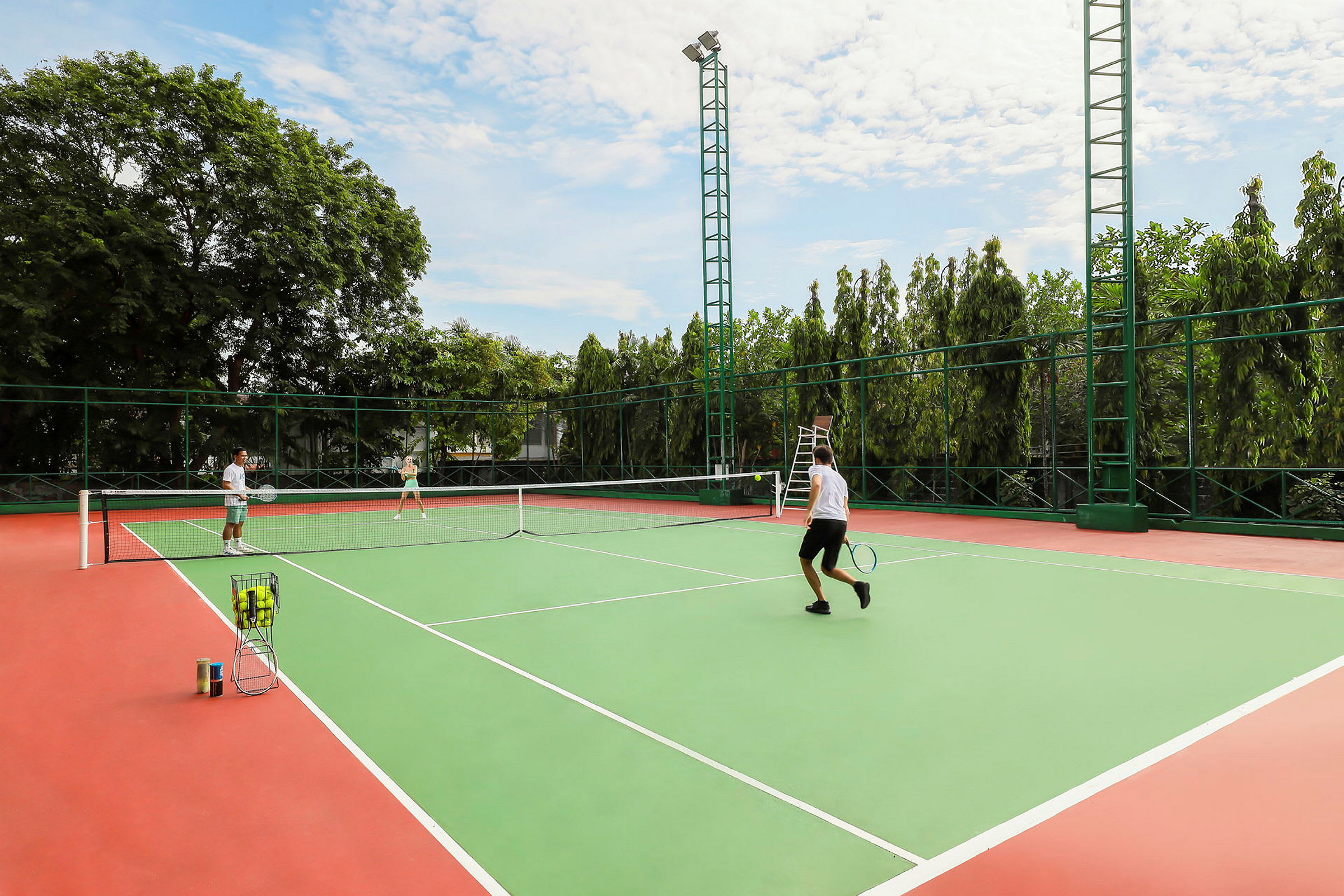 Henkilöt pelaavat tennistä ulkokentällä. Taustalla näkyy puita. (Tekoälyn luoma teksti)
