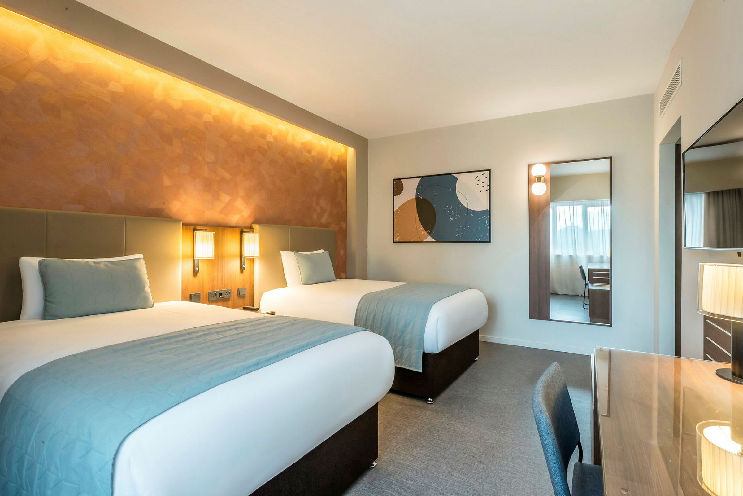 Hotellihuone, jossa kaksi erillistä vuodetta, kirjoituspöytä ja peili. (Tekoälyn luoma teksti)