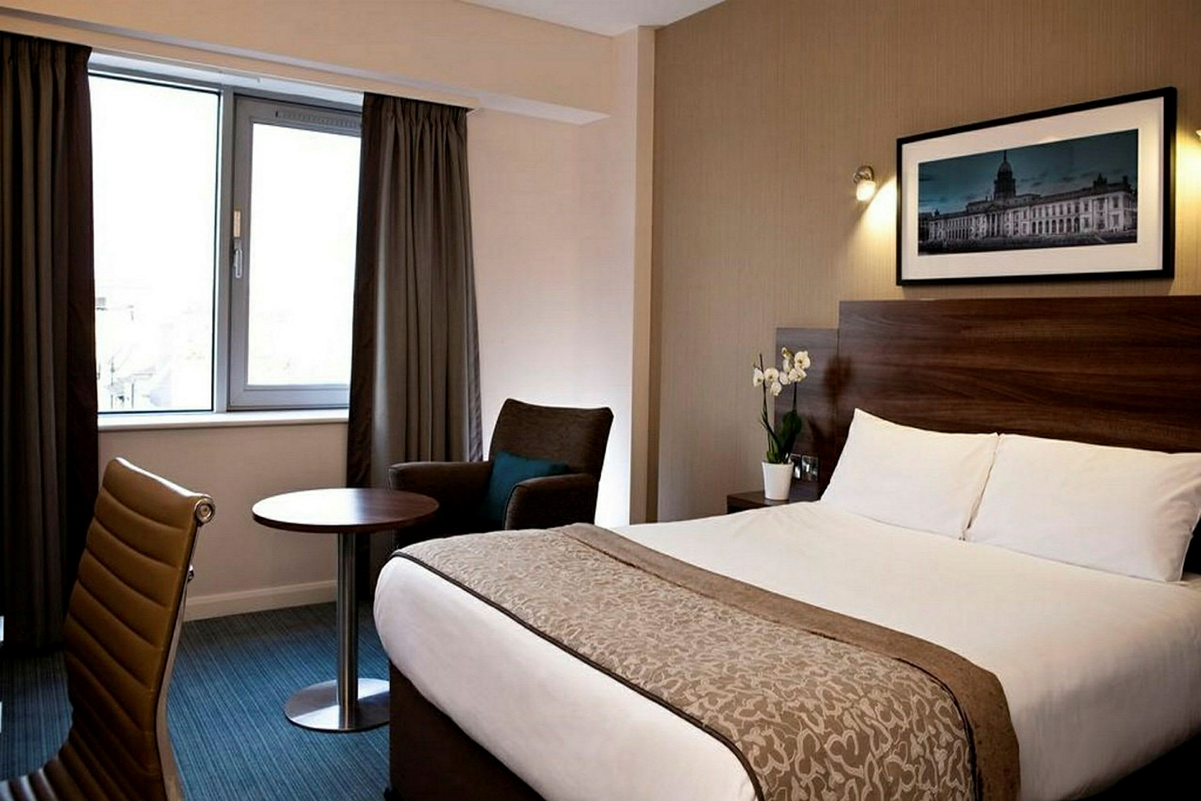 Hotellihuone, jossa vuode, tuoli, pöytä ja ikkuna verhoineen. (Tekoälyn luoma teksti)