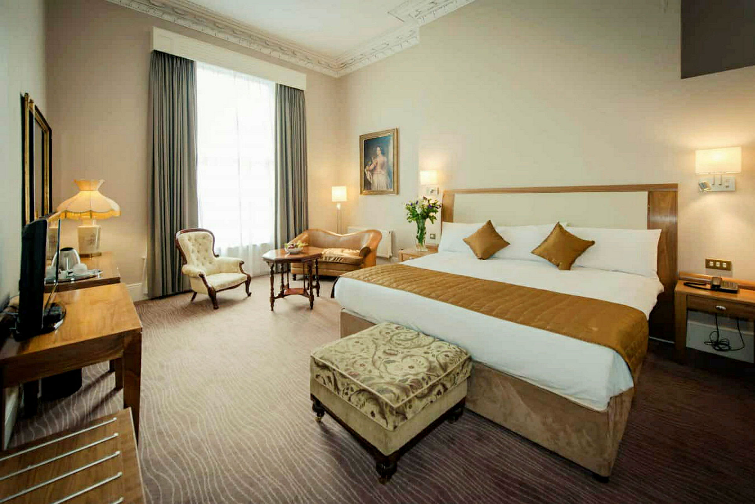Hotellihuone, jossa suuri sänky ja istuimet. (Tekoälyn luoma teksti)