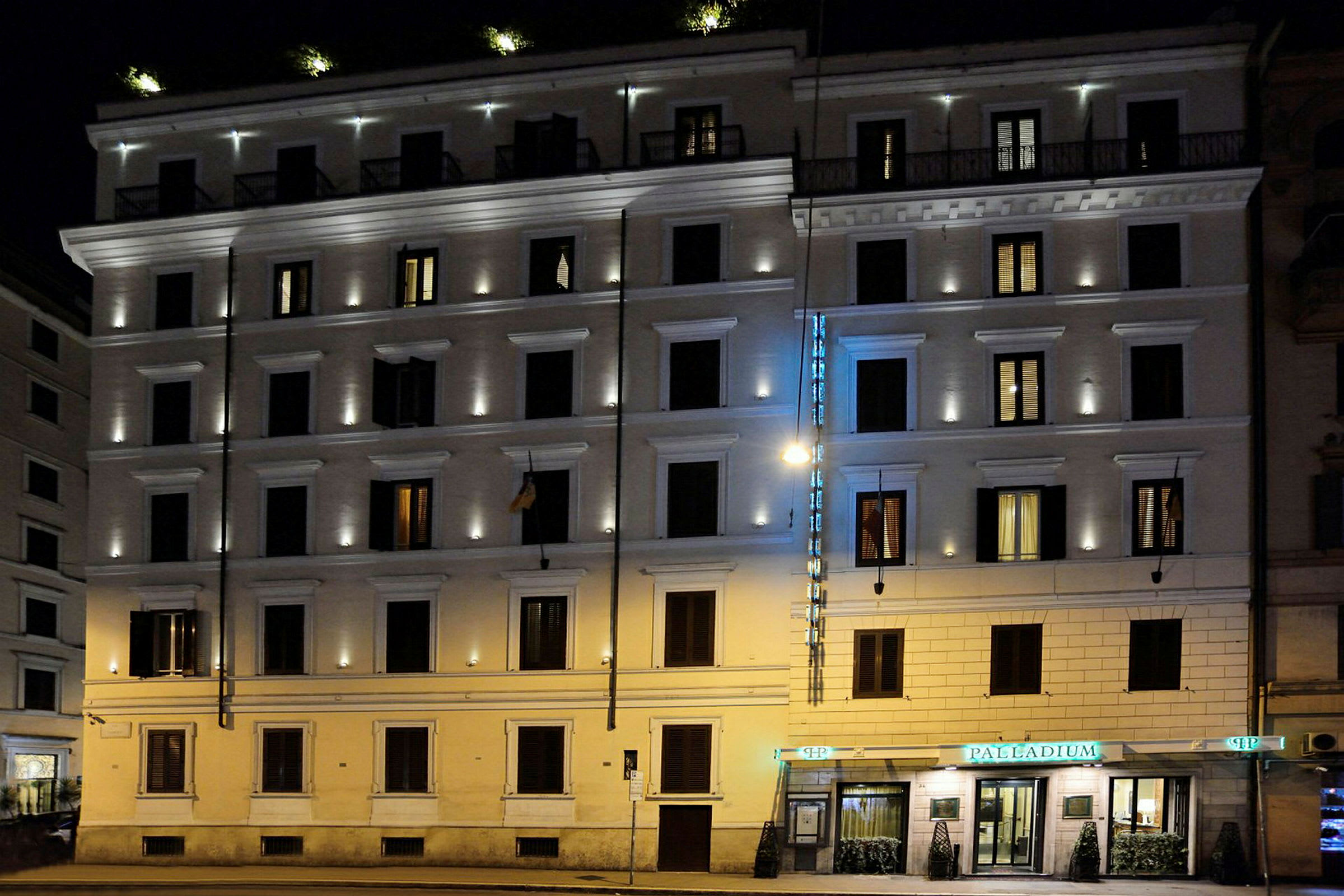 Illalla valaistu kerrostalo, jossa on hotellikyltti ja valaistut ikkunat. (Tekoälyn luoma teksti)