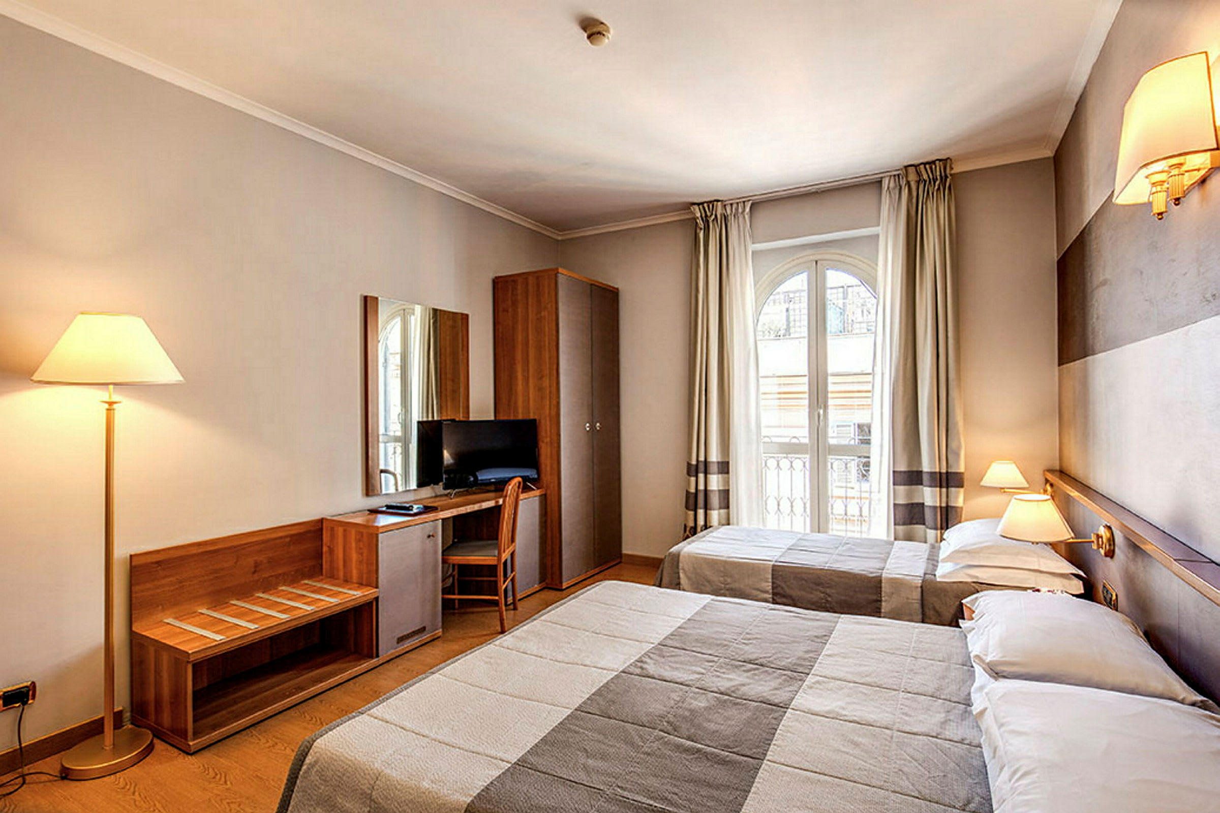 Hotellihuone, jossa kaksi sänkyä, kirjoituspöytä tuolilla, televisio ja tyylikäs sisustus. (Tekoälyn luoma teksti)