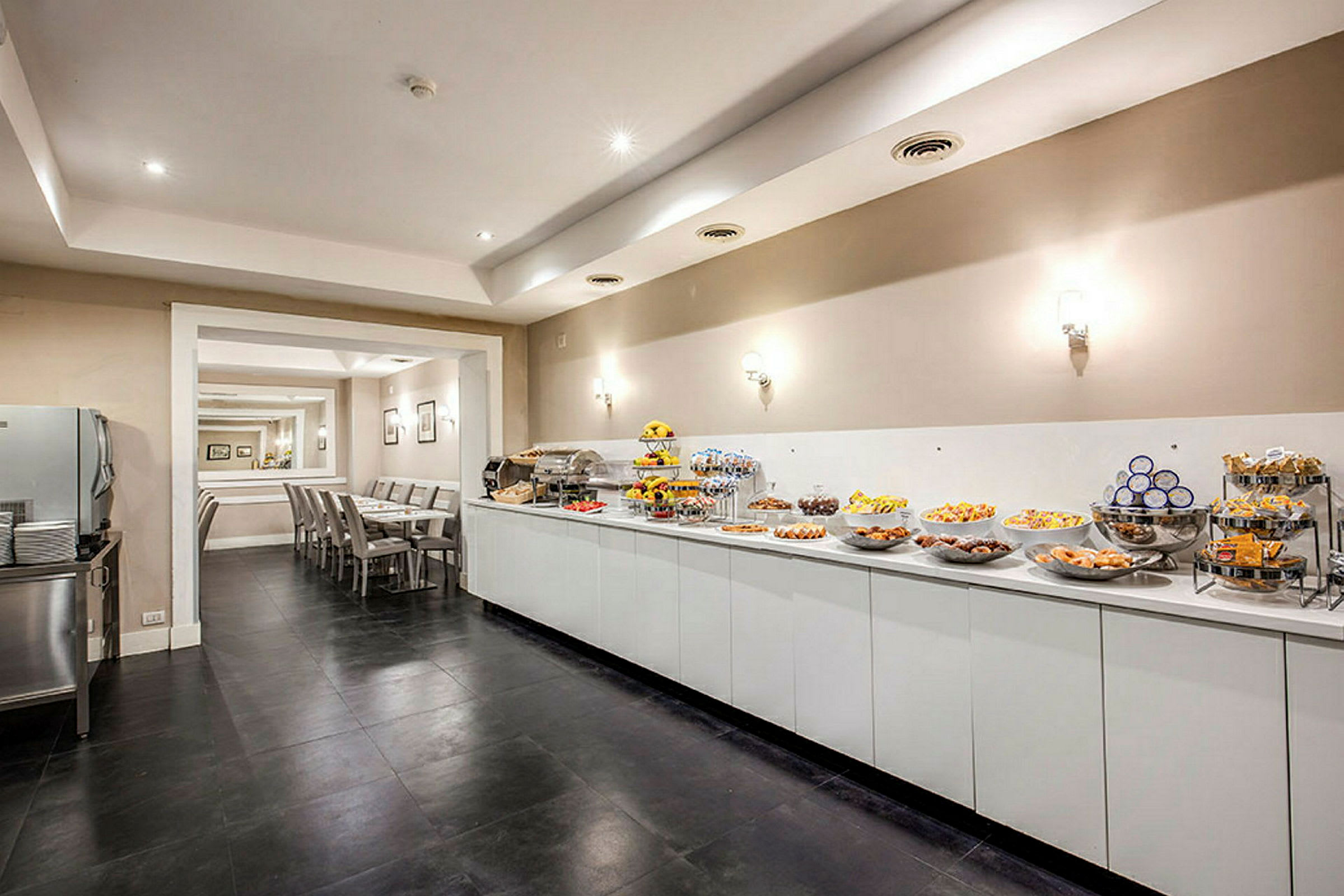 Buffet, jossa erilaisia ruokia ja välipaloja, edessä istuma-alue pöytineen ja tuoleineen. (Tekoälyn luoma teksti)