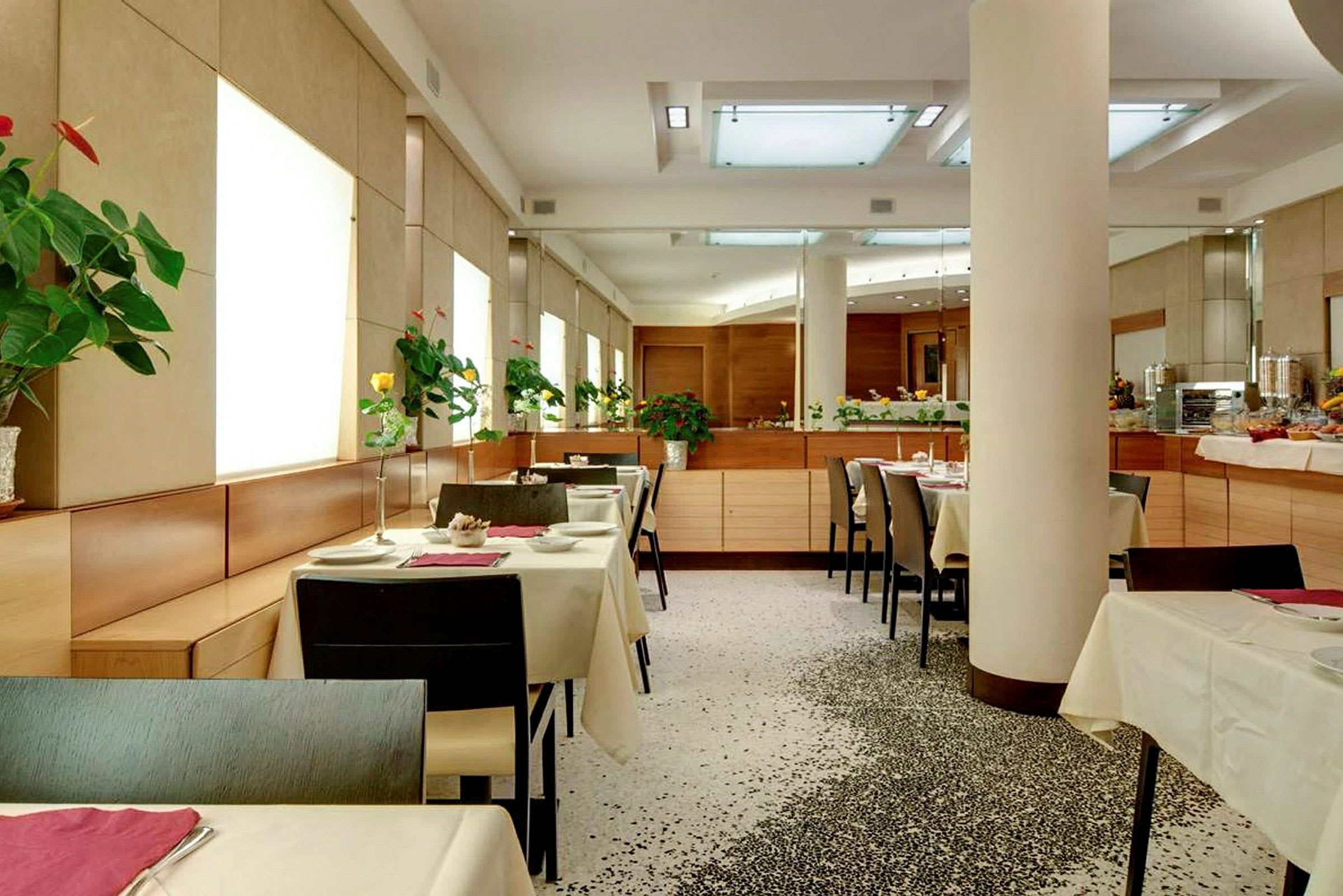 Moderni ravintola, jossa on katettuja pöytiä ja kukkia jokaisella pöydällä. (Tekoälyn luoma teksti)