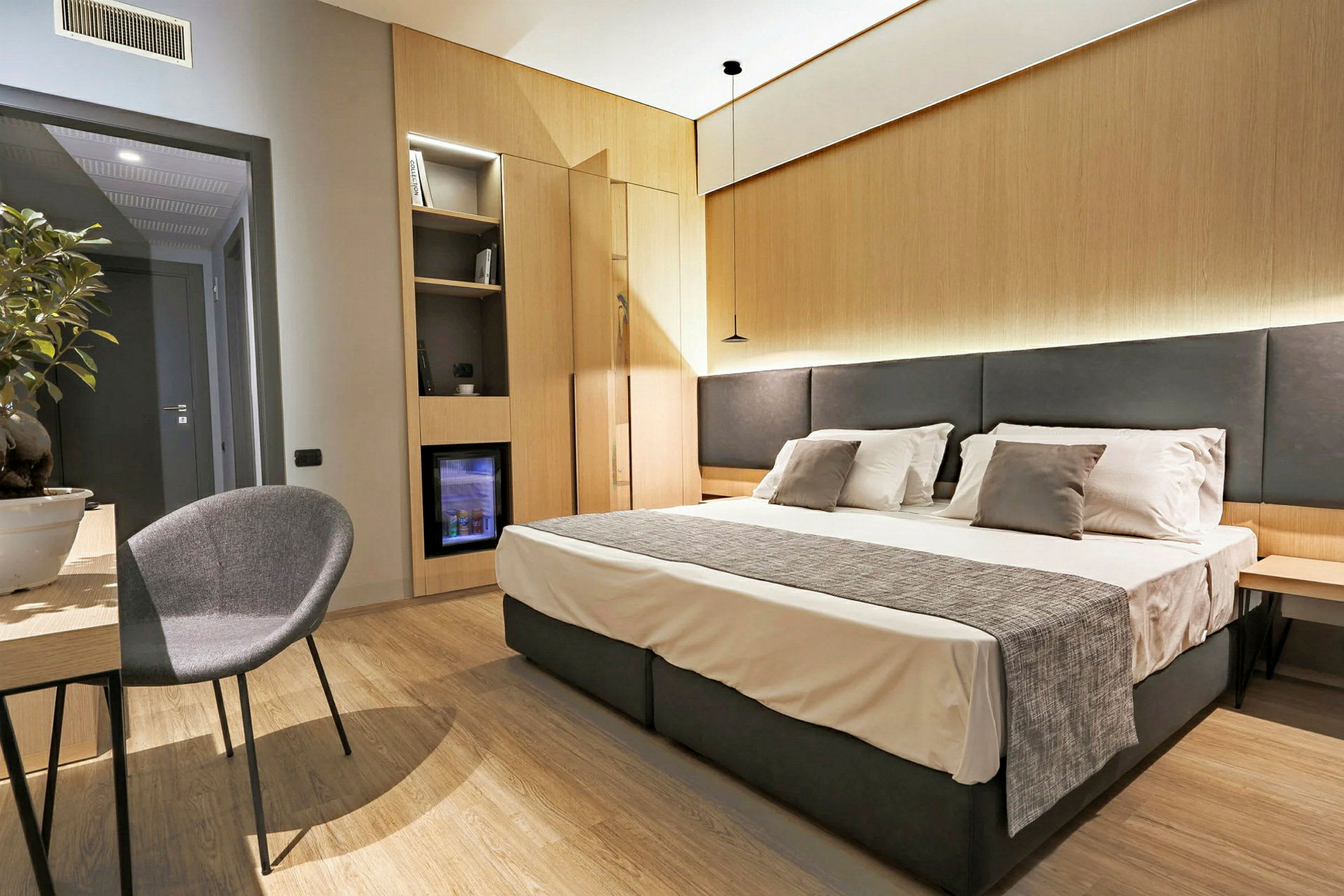 Hotellihuone, jossa parivuode, yöpöytä ja tuoli pöydän ääressä. (Tekoälyn luoma teksti)