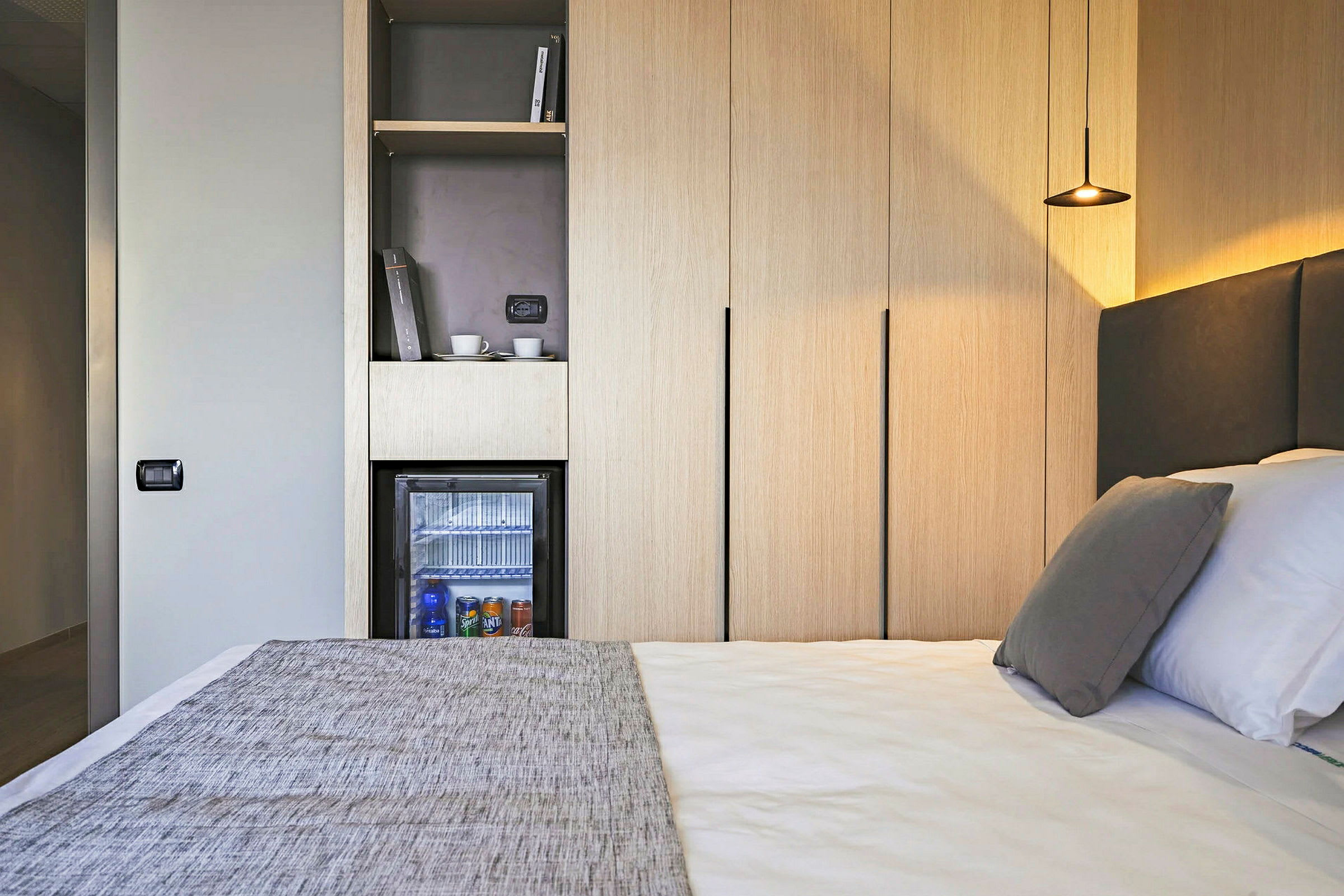 Hotellihuone, jossa sänky, minibaari ja vaatekaapit. (Tekoälyn luoma teksti)