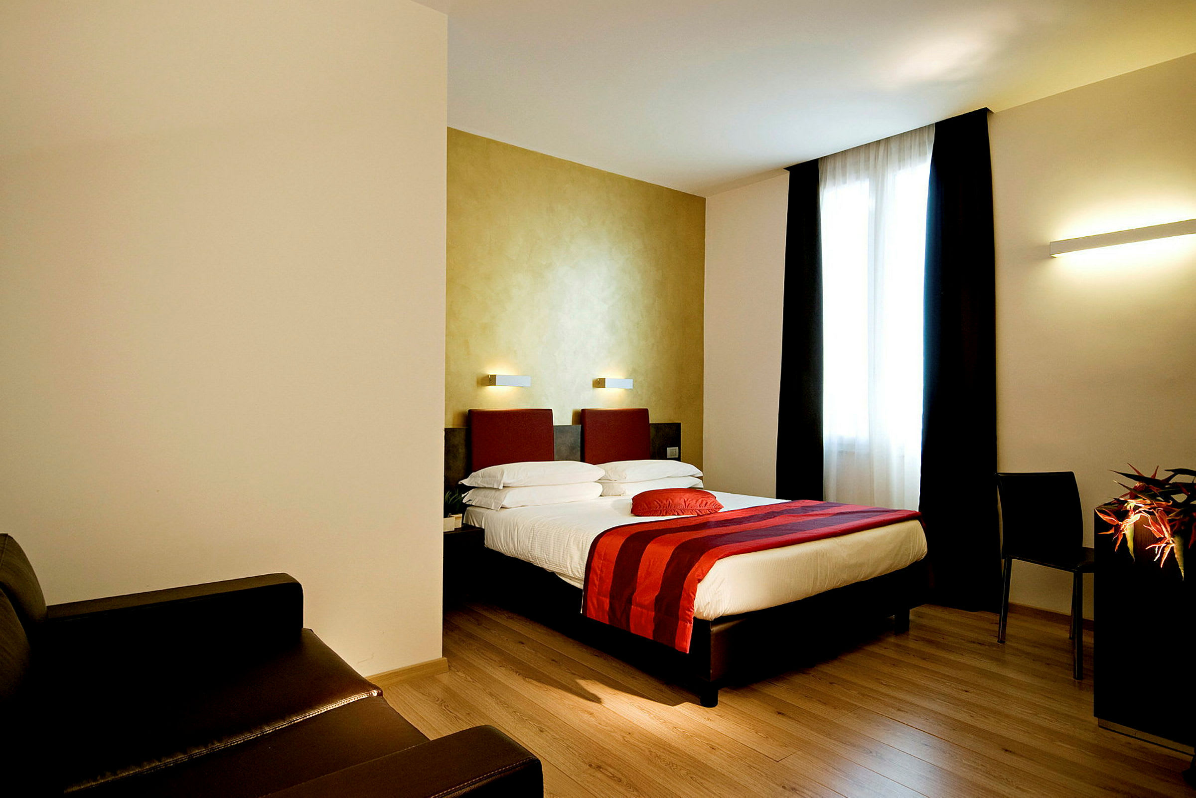 Hotellihuone, jossa parivuode, punaisia yksityiskohtia ja iso ikkuna. (Tekoälyn luoma teksti)