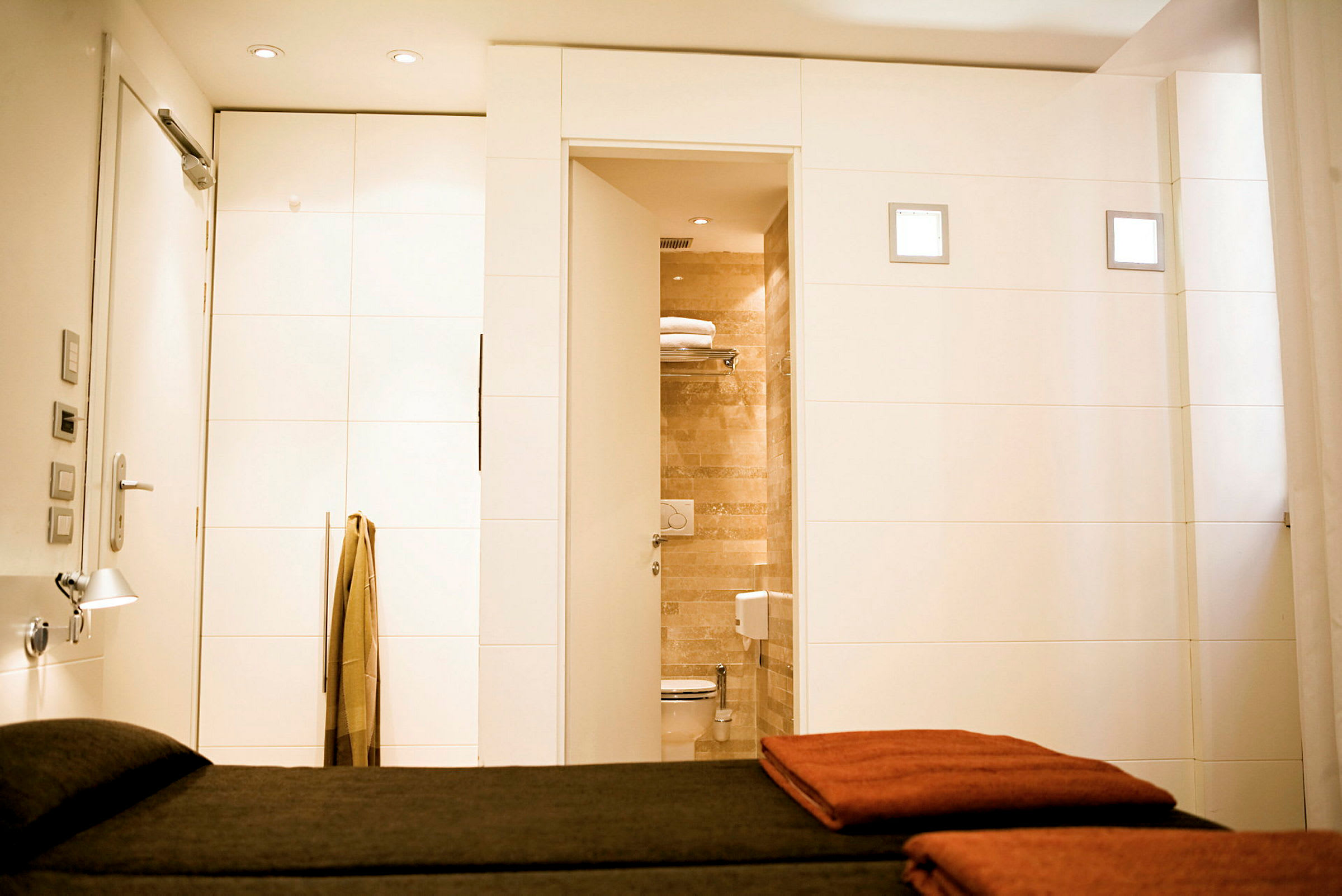Hotellihuoneen sisätilat, etualalla sänky ja puoliksi avoin ovi kylpyhuoneeseen. (Tekoälyn luoma teksti)