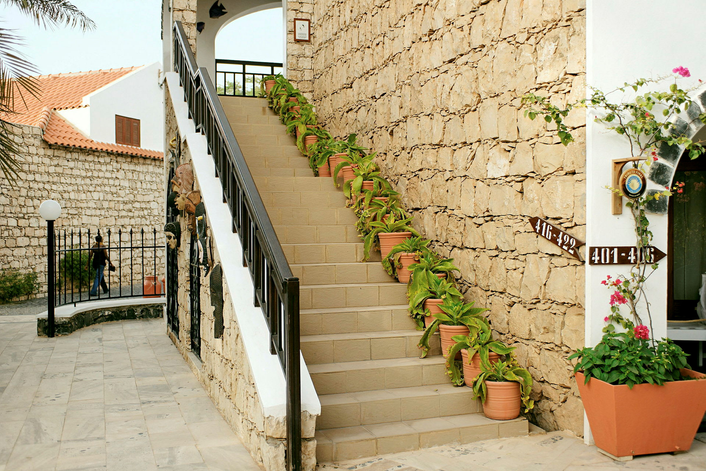 Portaat kivimuurin vieressä, kaiteen varrella koristekasveja ruukuissa. (Tekoälyn luoma teksti)