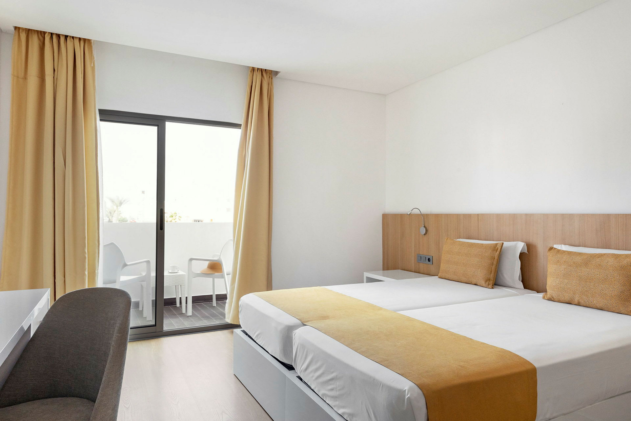 Hotellihuone, jossa on kaksi yhden hengen vuodetta ja parveke. (Tekoälyn luoma teksti)