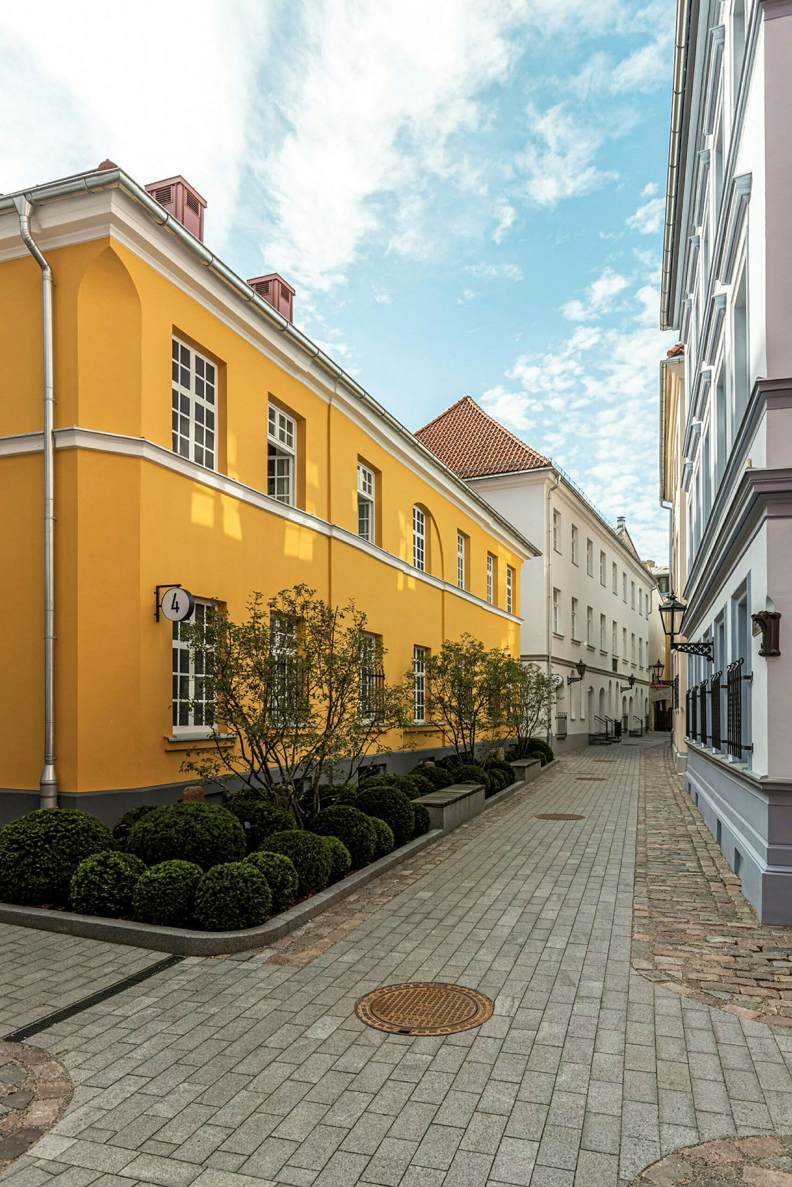 Kapea kivipäällysteinen katu, jossa on keltaisia ja valkoisia rakennuksia. (Tekoälyn luoma teksti)